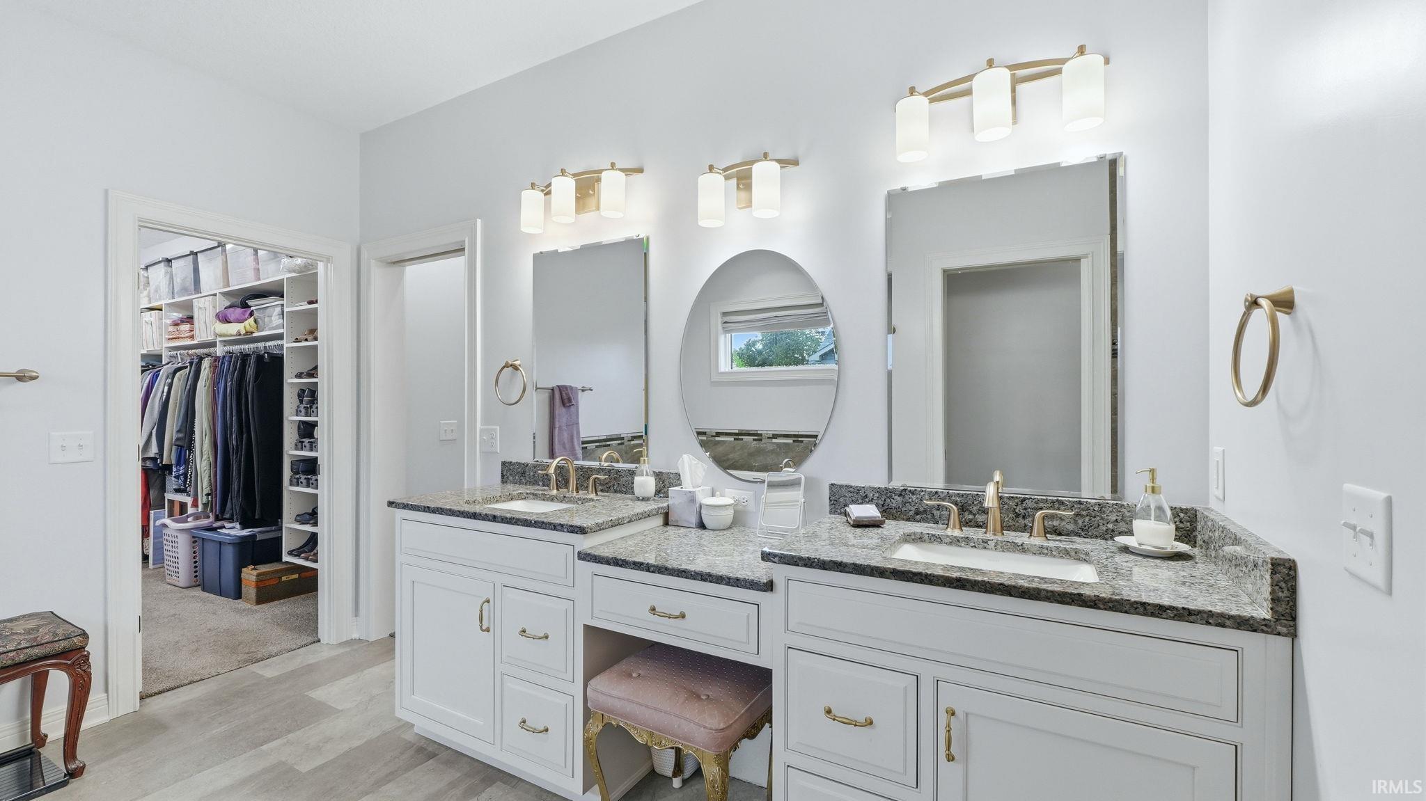 Dual vanity with stone countertops and undermount sinks, featuring gold-toned fixtures and decorative mirrors