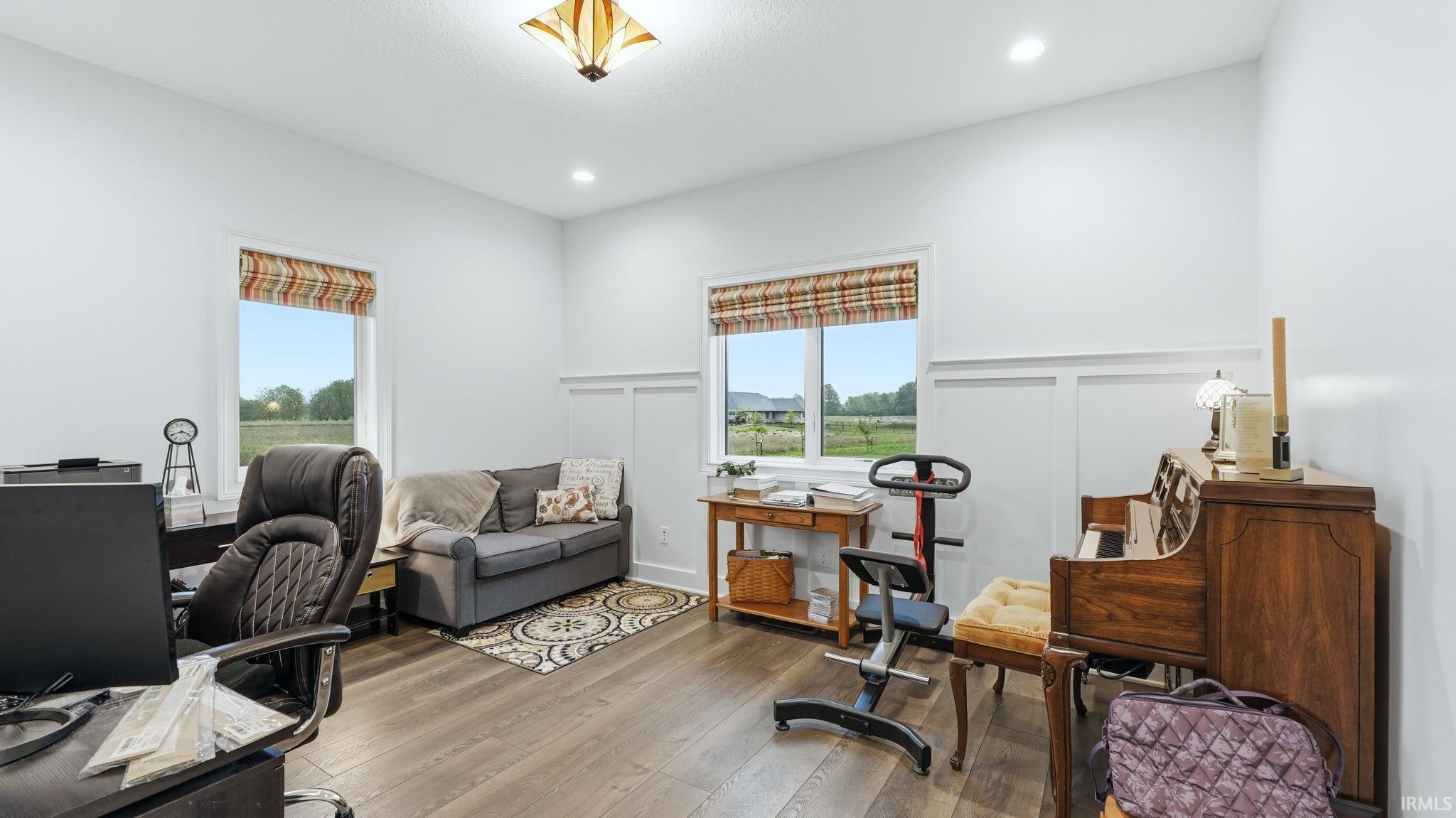 Spacious room featuring two large windows, white wainscoting, recessed lighting, and a prominent ceiling fixture