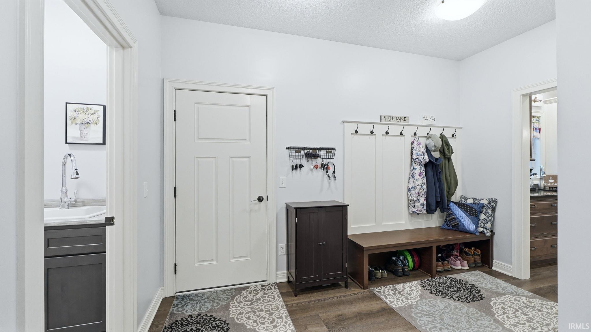 Entryway featuring wood-finish flooring and a built-in bench with coat hooks