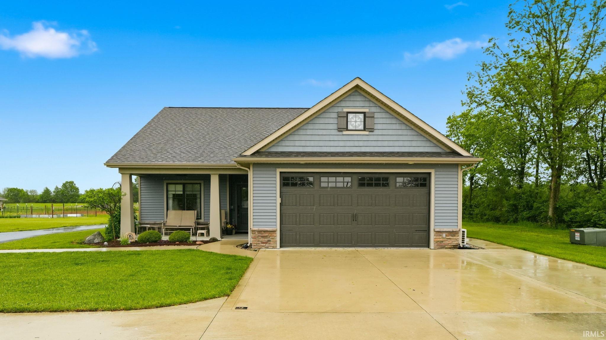 Ranch-style exterior featuring blue siding, a dark gray shingle roof, and a two-car garage with paneling and window inserts