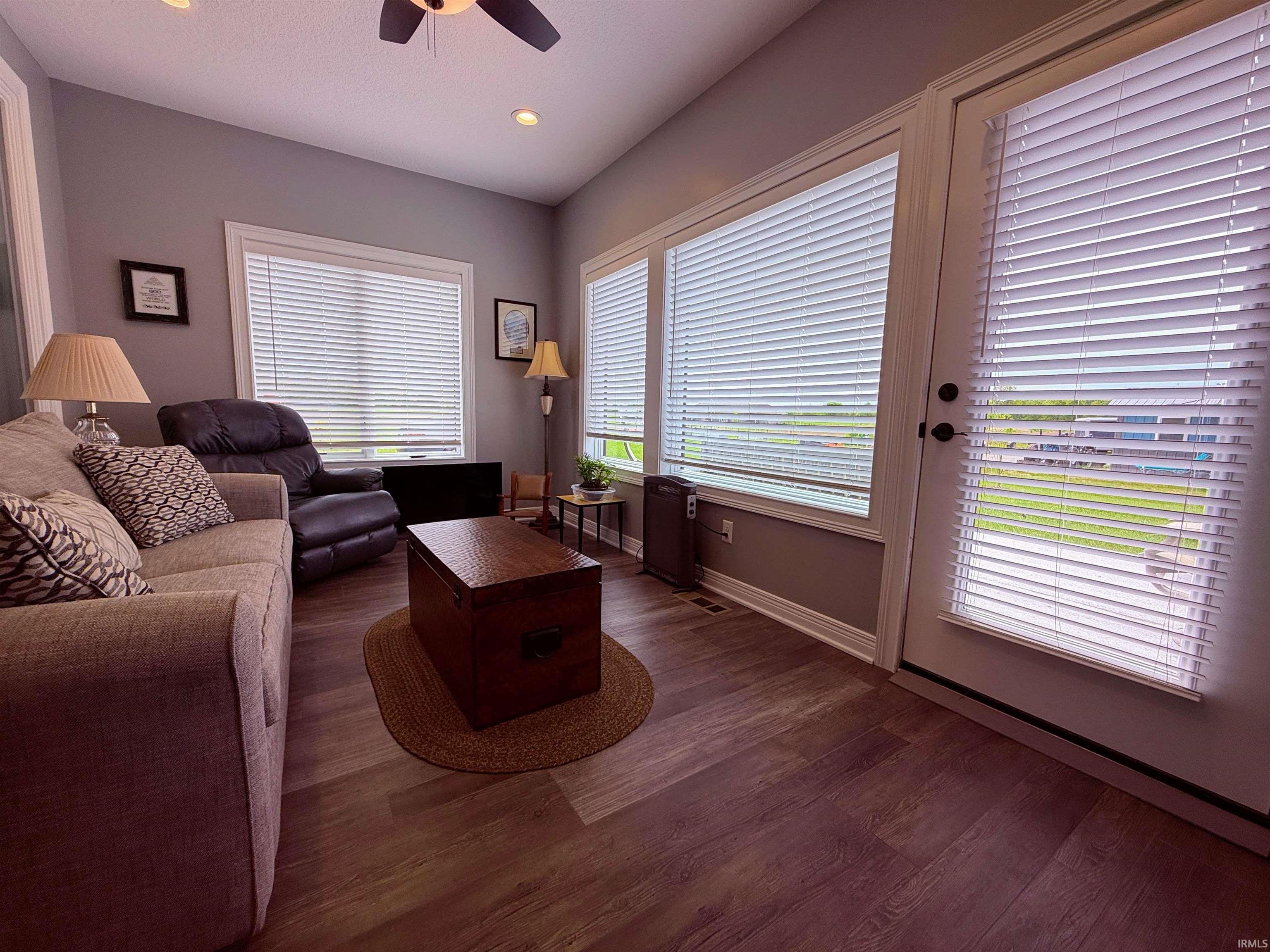Living area featuring vaulted ceiling with a ceiling fan, multiple windows with blinds, recessed lighting, and an exterior door