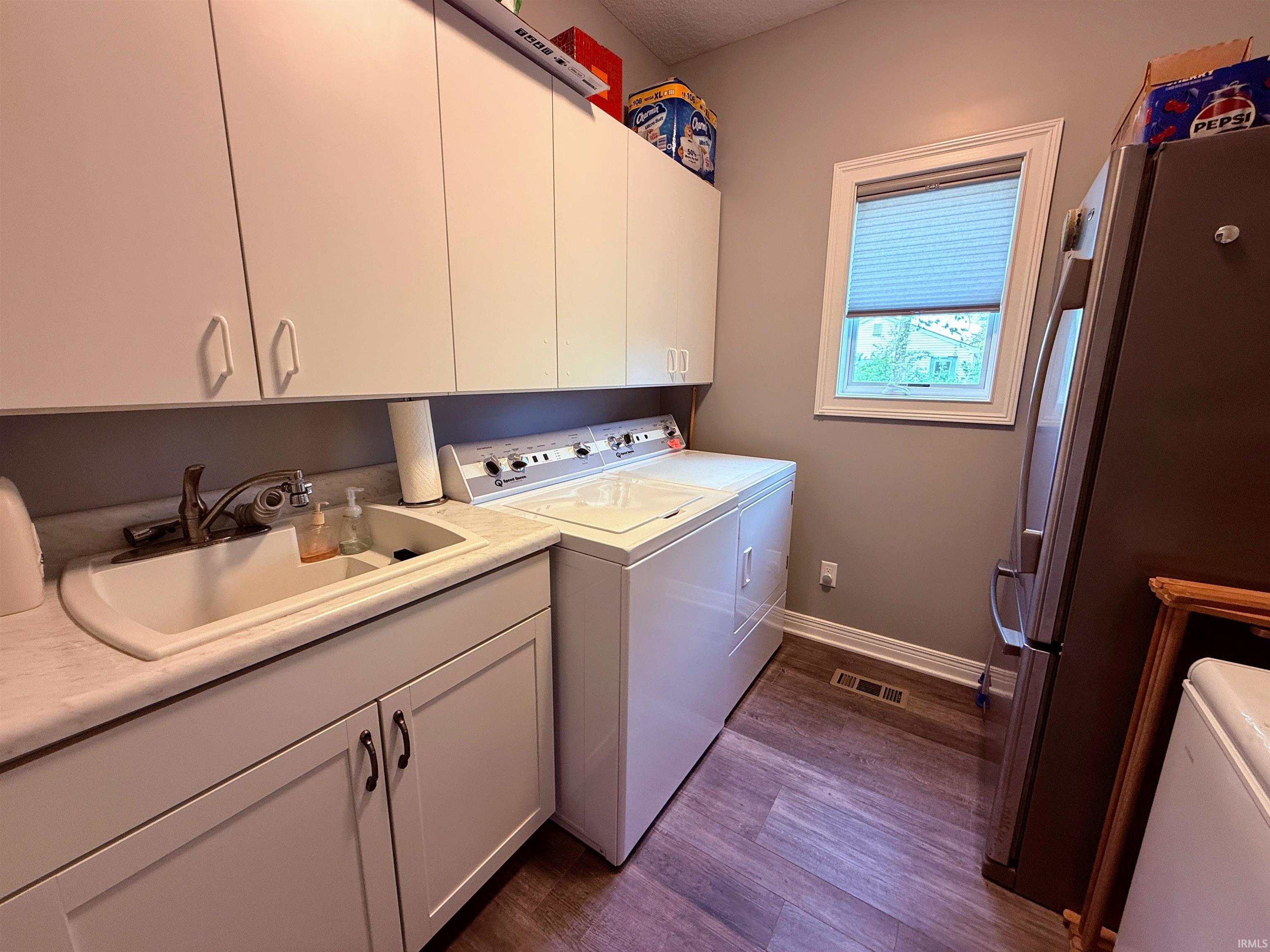 Functional laundry area featuring white cabinetry, a utility sink with a laminate countertop