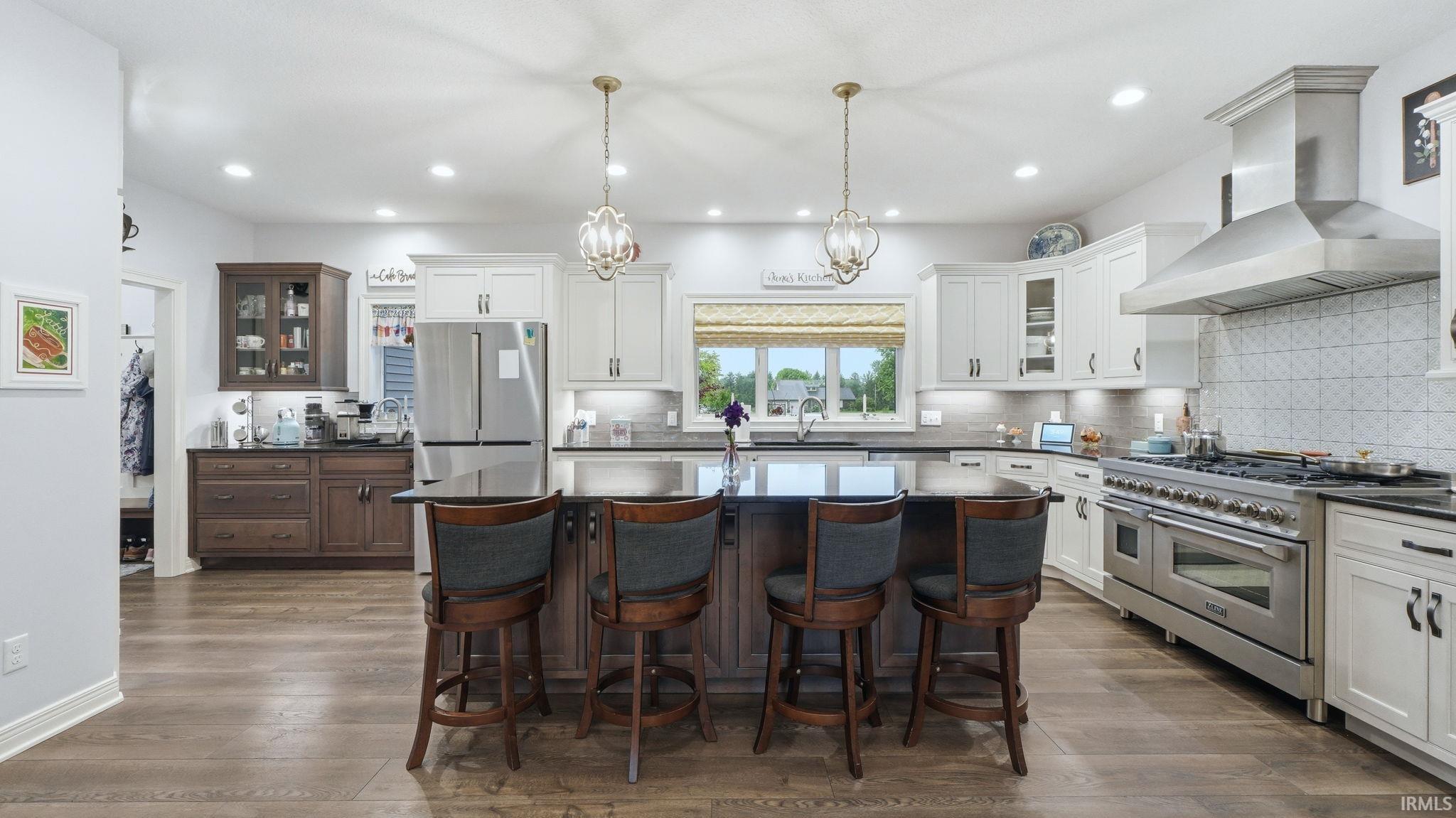 Spacious kitchen featuring a central island with seating, a professional-grade stainless steel range with a large hood