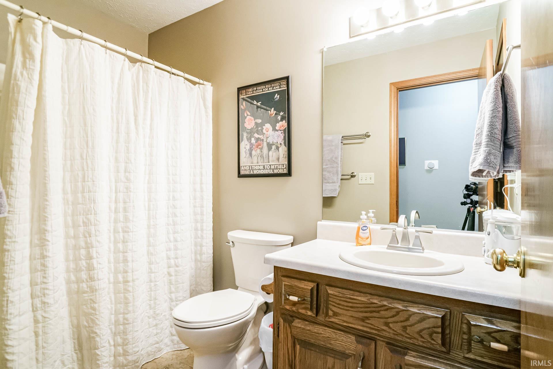 Bathroom featuring a single vanity with wood-finish cabinetry, a white countertop, and an integrated sink