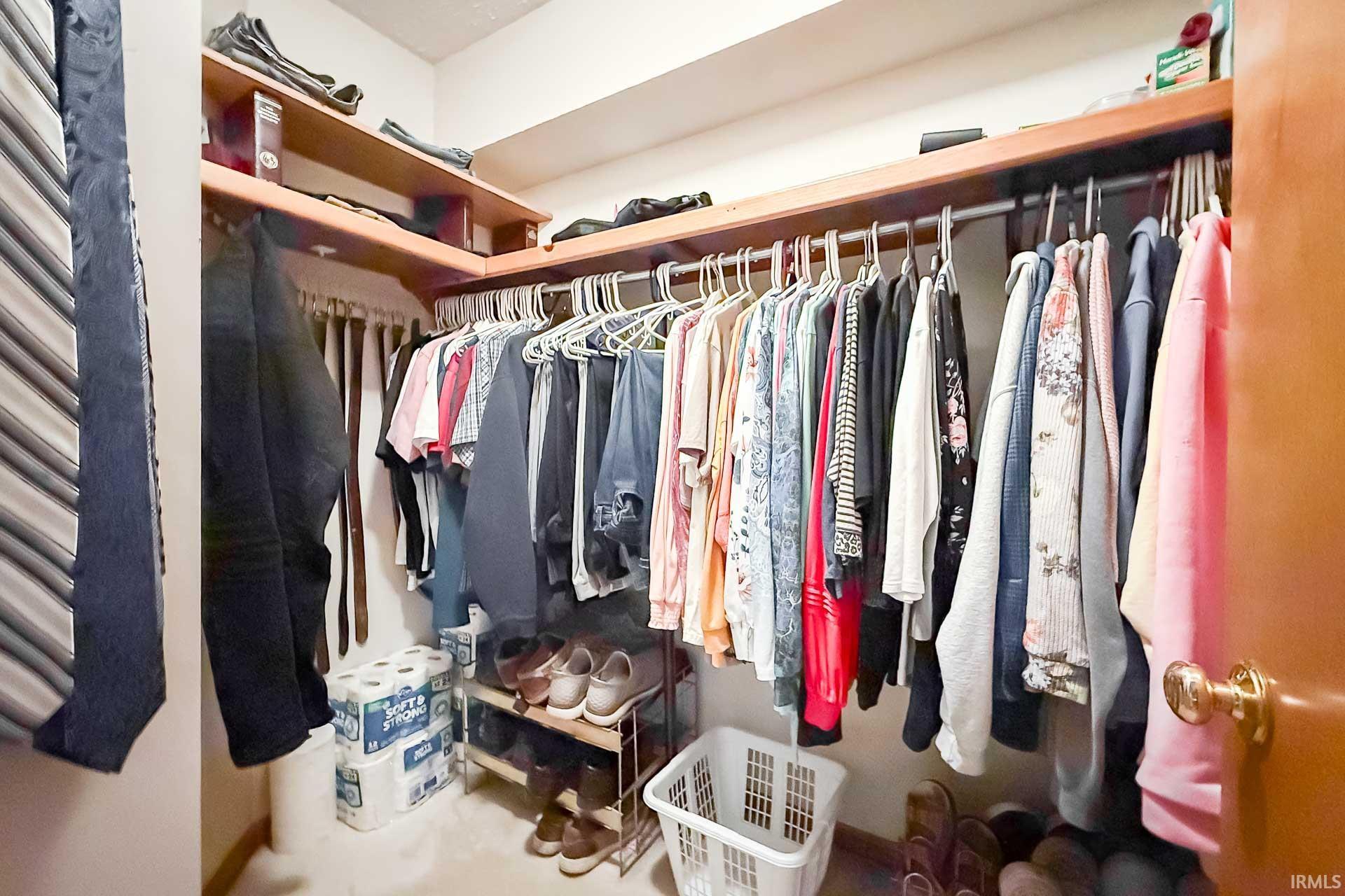 Walk-in closet featuring built-in wood shelving, multiple hanging rods, and a light-colored floor