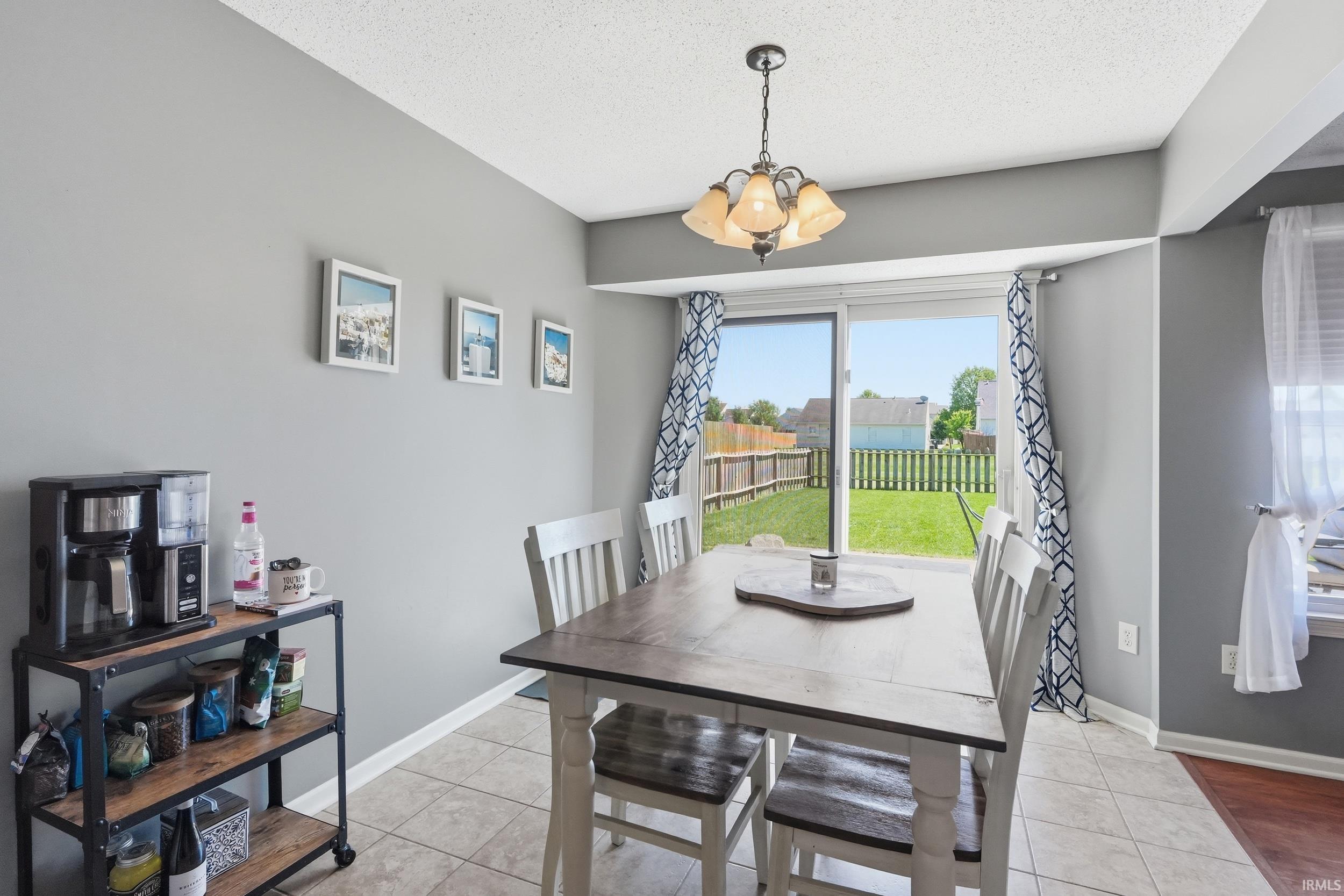 Dining area featuring tile flooring, a multi-light pendant fixture, and a sliding glass door offering access to the fenced backyard