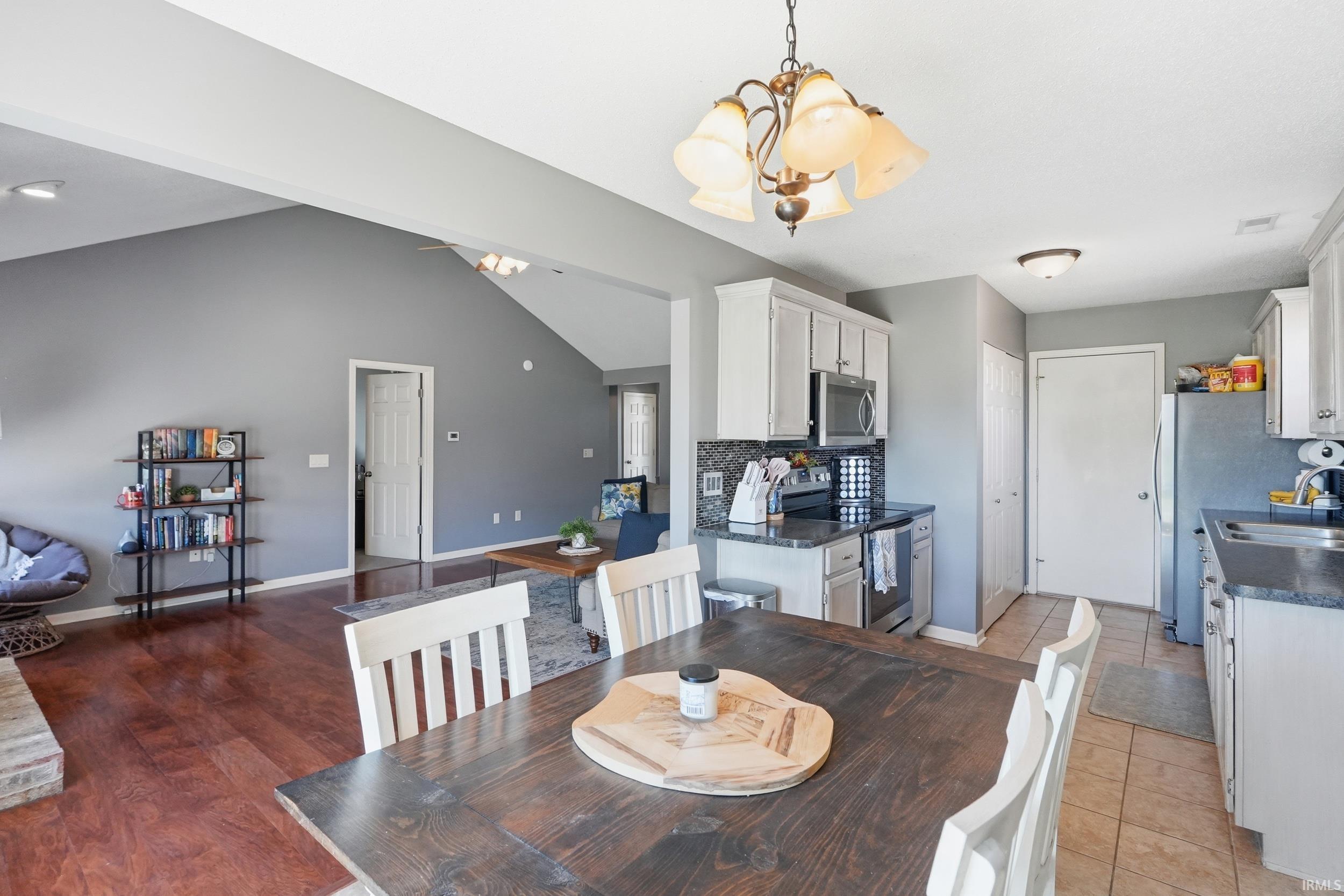 Open-concept kitchen and living area featuring a vaulted ceiling and wood-finish flooring
