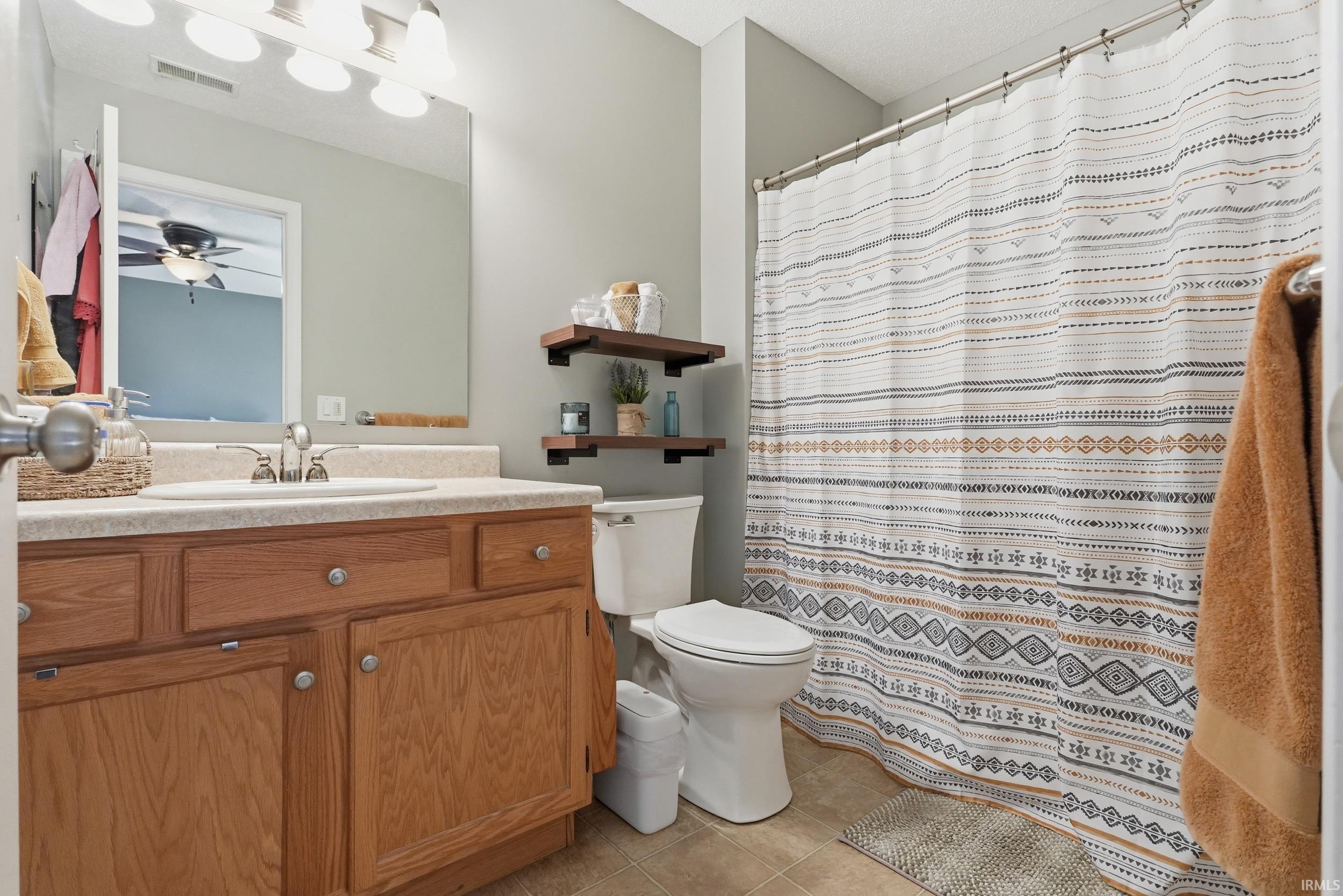 Bathroom featuring a single vanity with wood cabinetry, a light-colored countertop, and an undermount sink