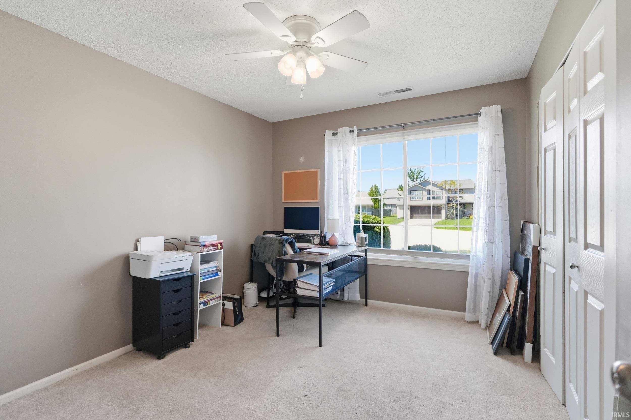 Bright room with a large window, neutral carpeting, and a ceiling fan with integrated lighting