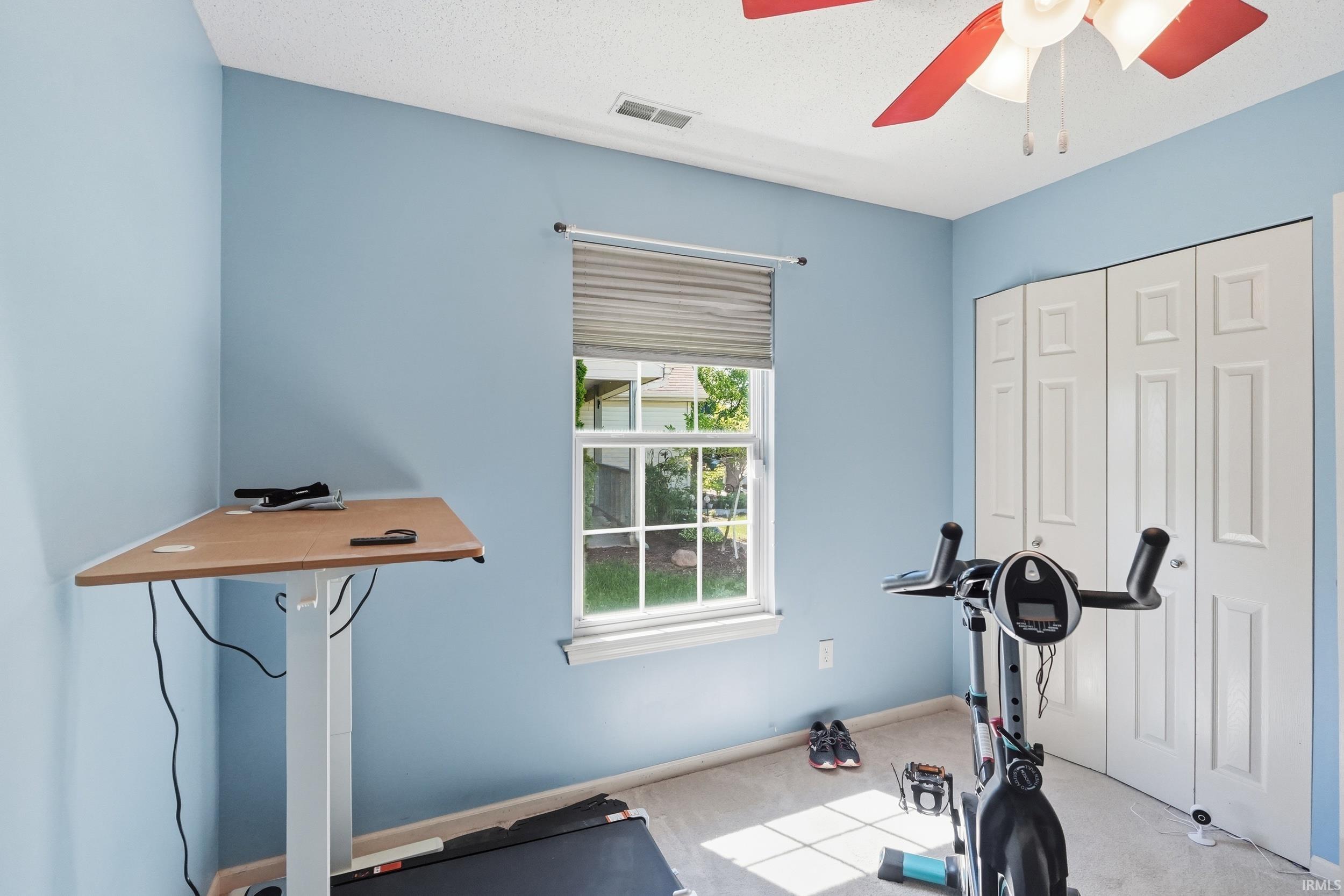 Room featuring light blue walls and a window with blinds