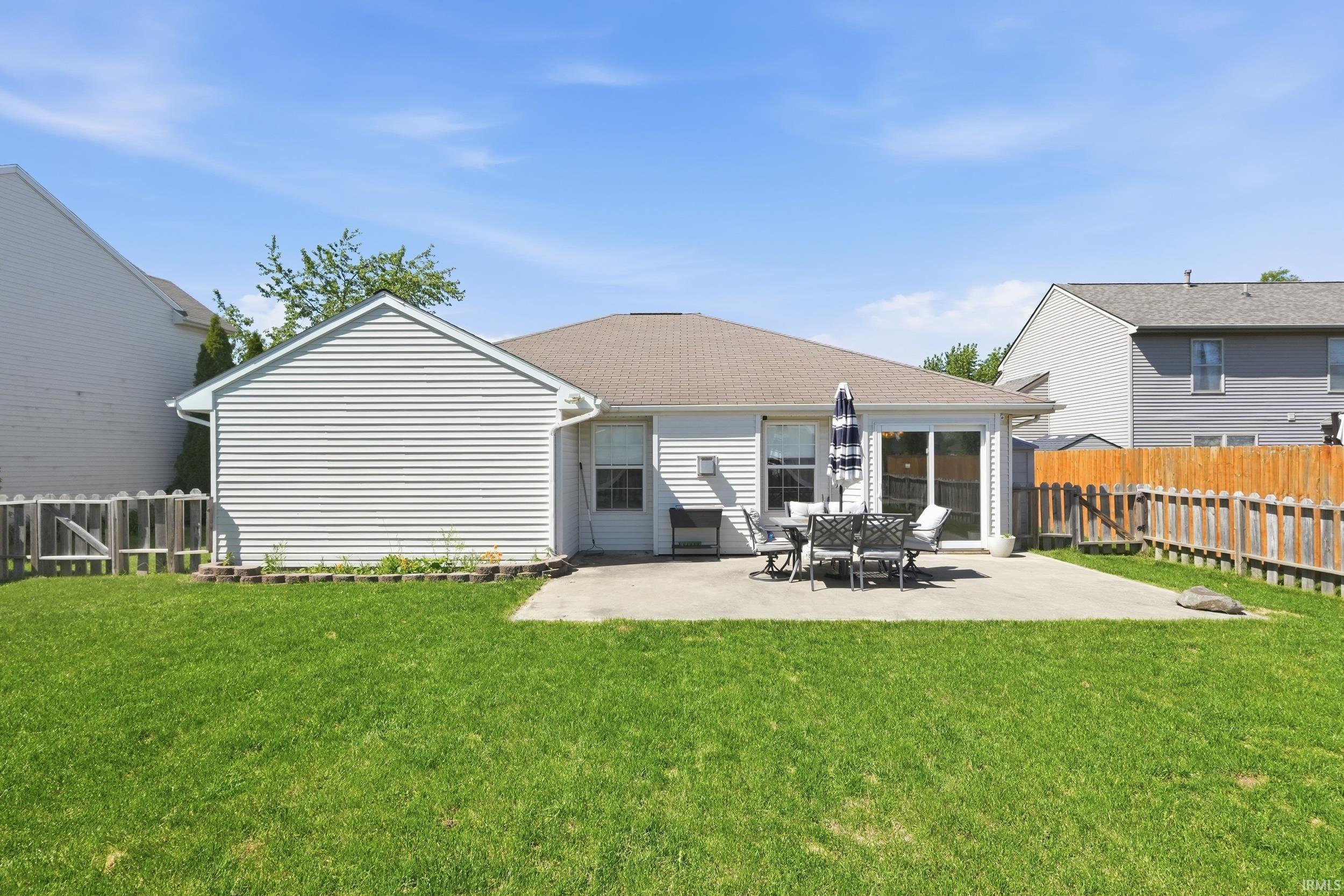Expansive rear yard featuring a concrete patio, sliding glass door access, and a wood privacy fence