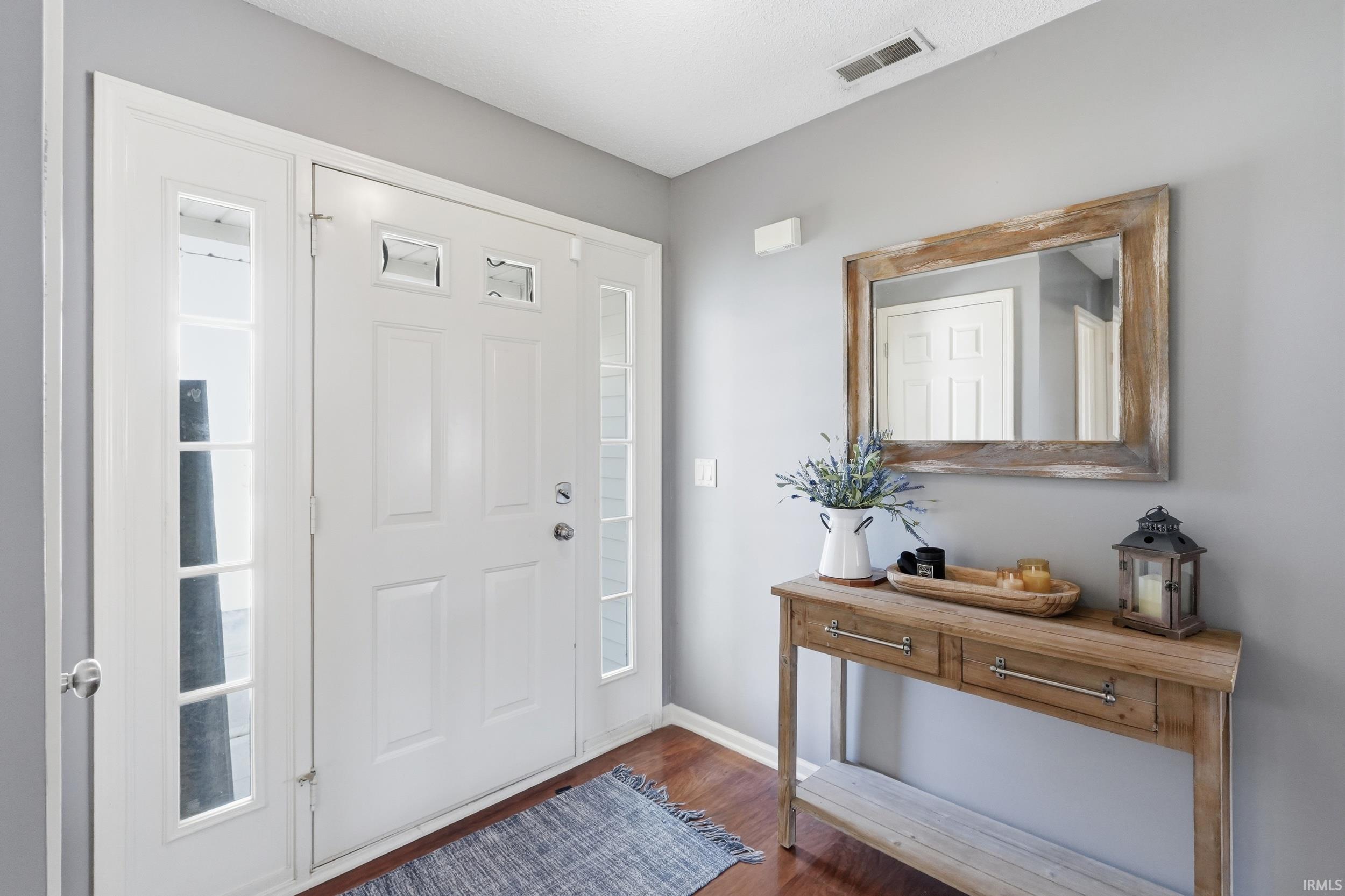 Entryway featuring a white paneled door with glass inserts, sidelight windows, and a wood-finish floor