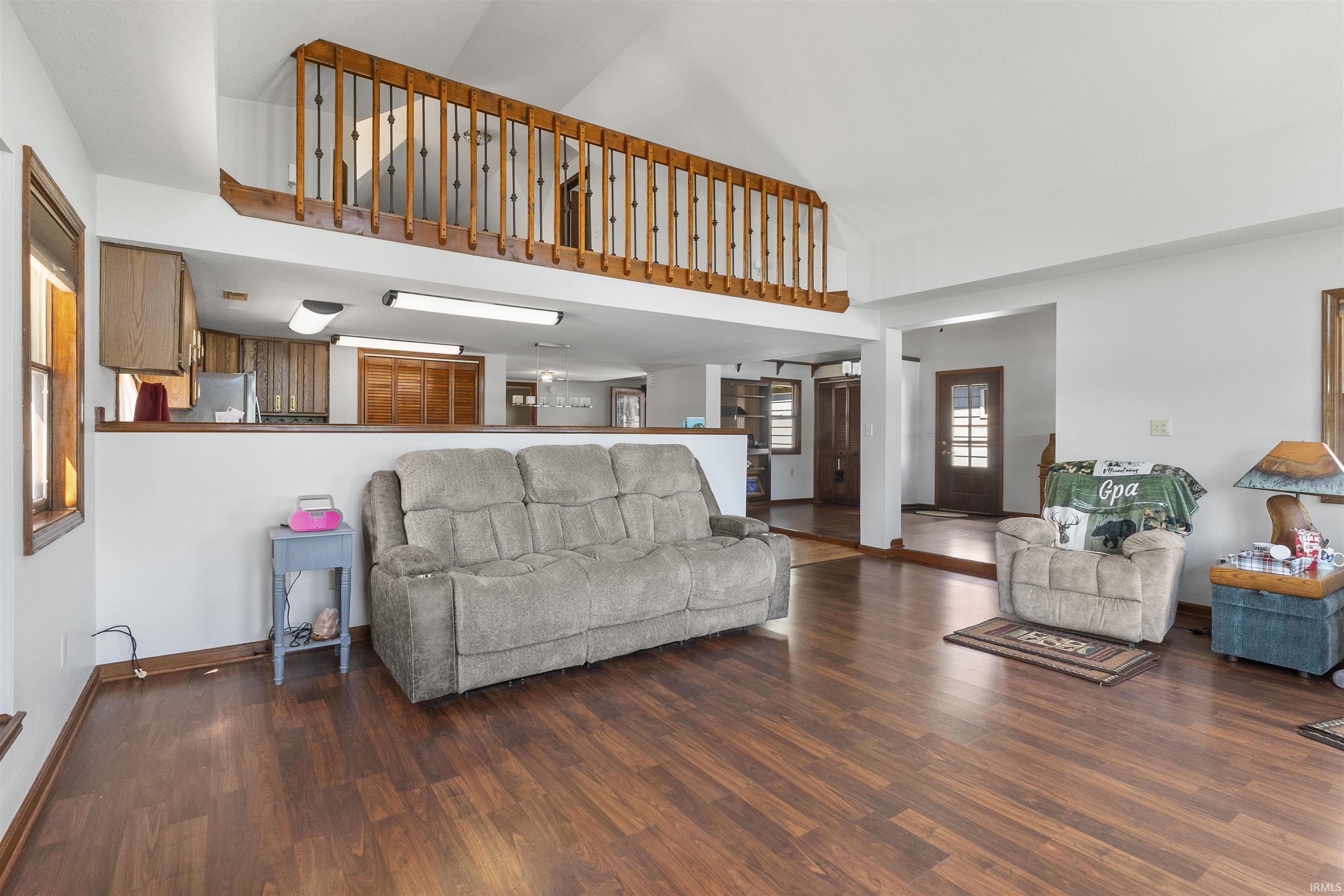 Spacious living area featuring wood-finish flooring, vaulted ceilings, and an open loft overlooking the space