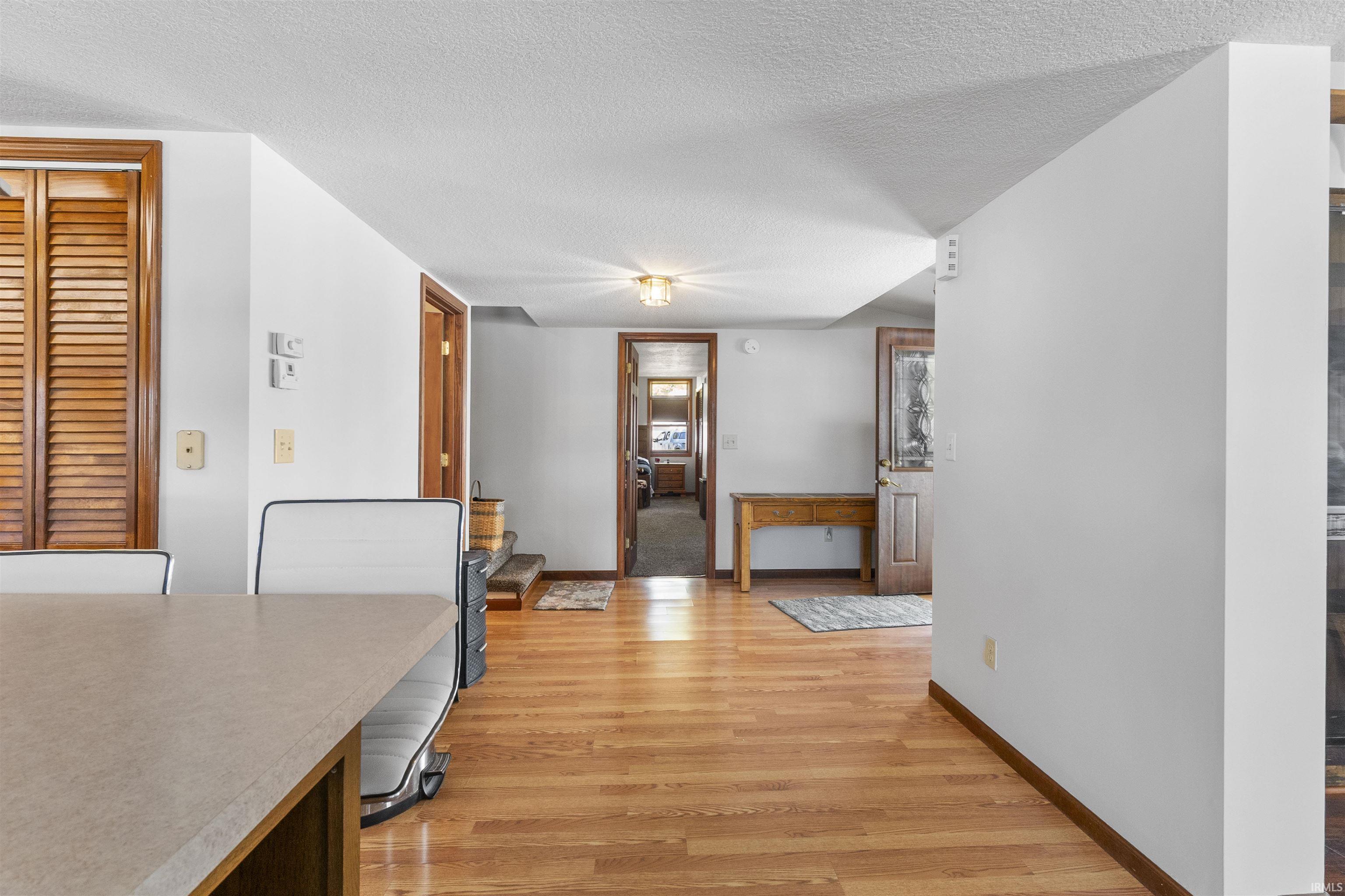 Hardwood flooring throughout a bright interior with white walls, featuring wood-framed doorways and built-in wooden louvered doors