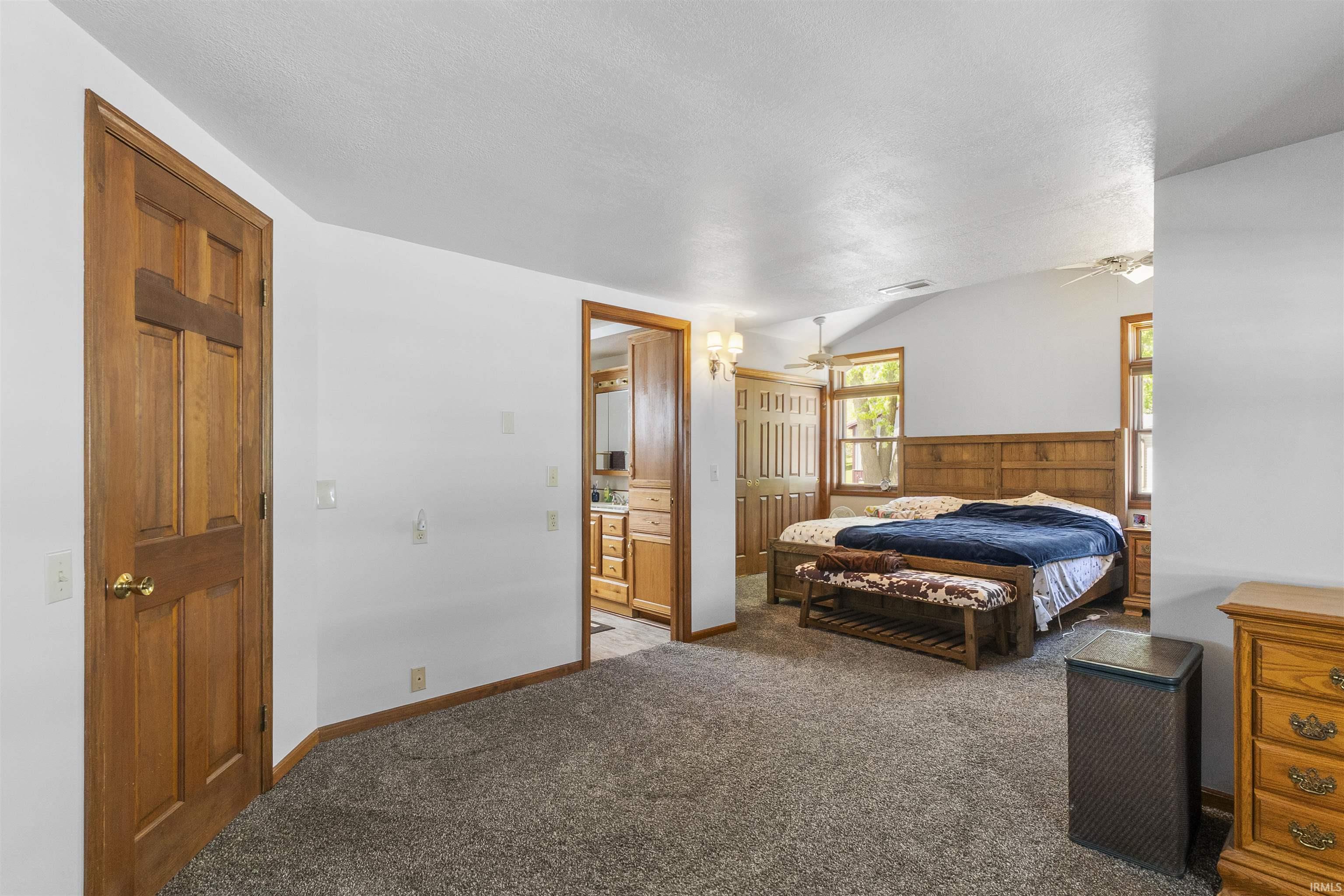 Spacious room featuring vaulted ceilings, wood-finish doors, carpet flooring, and abundant natural light from multiple windows