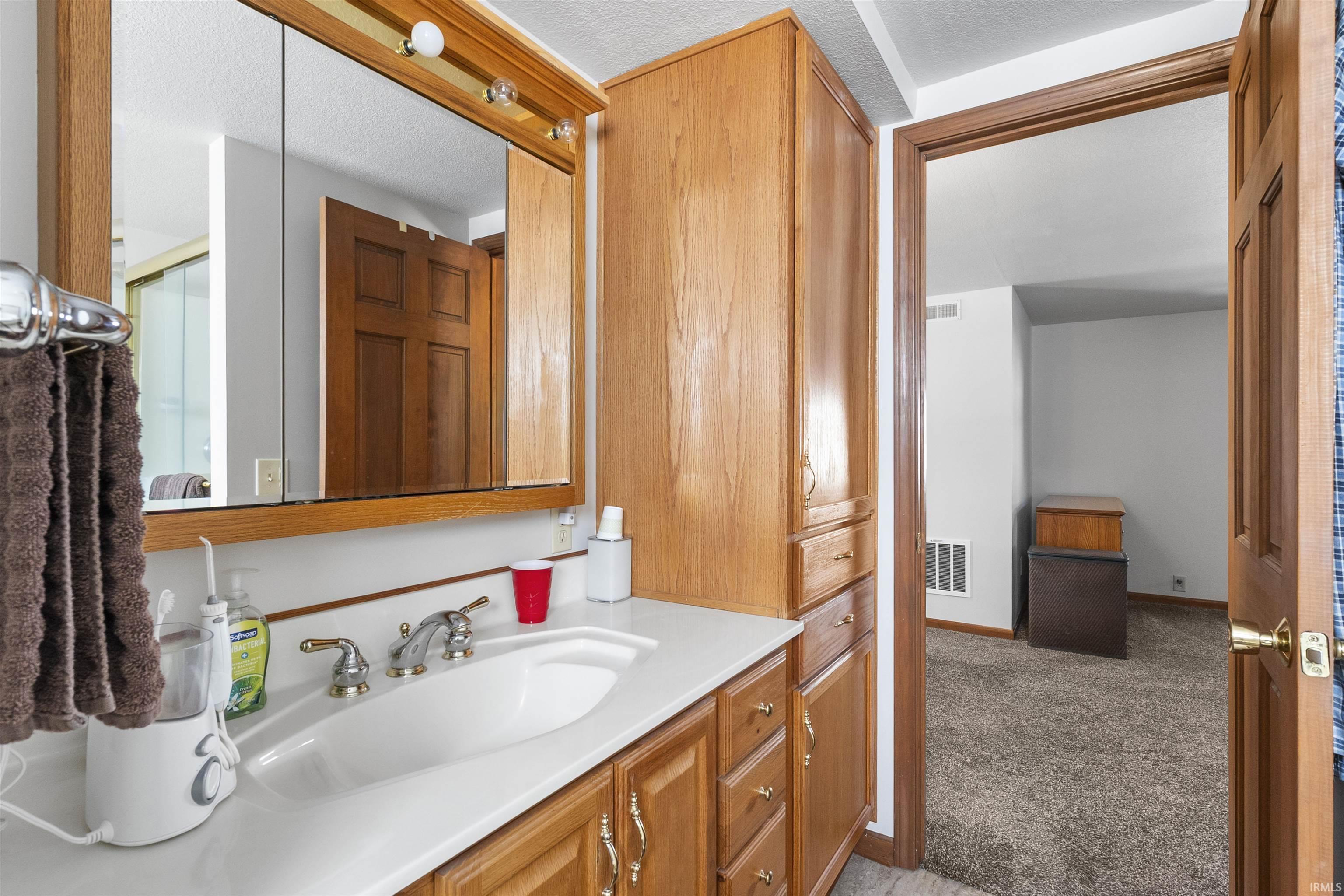 Bathroom vanity featuring a single basin sink, chrome faucet, and wood-finish cabinetry