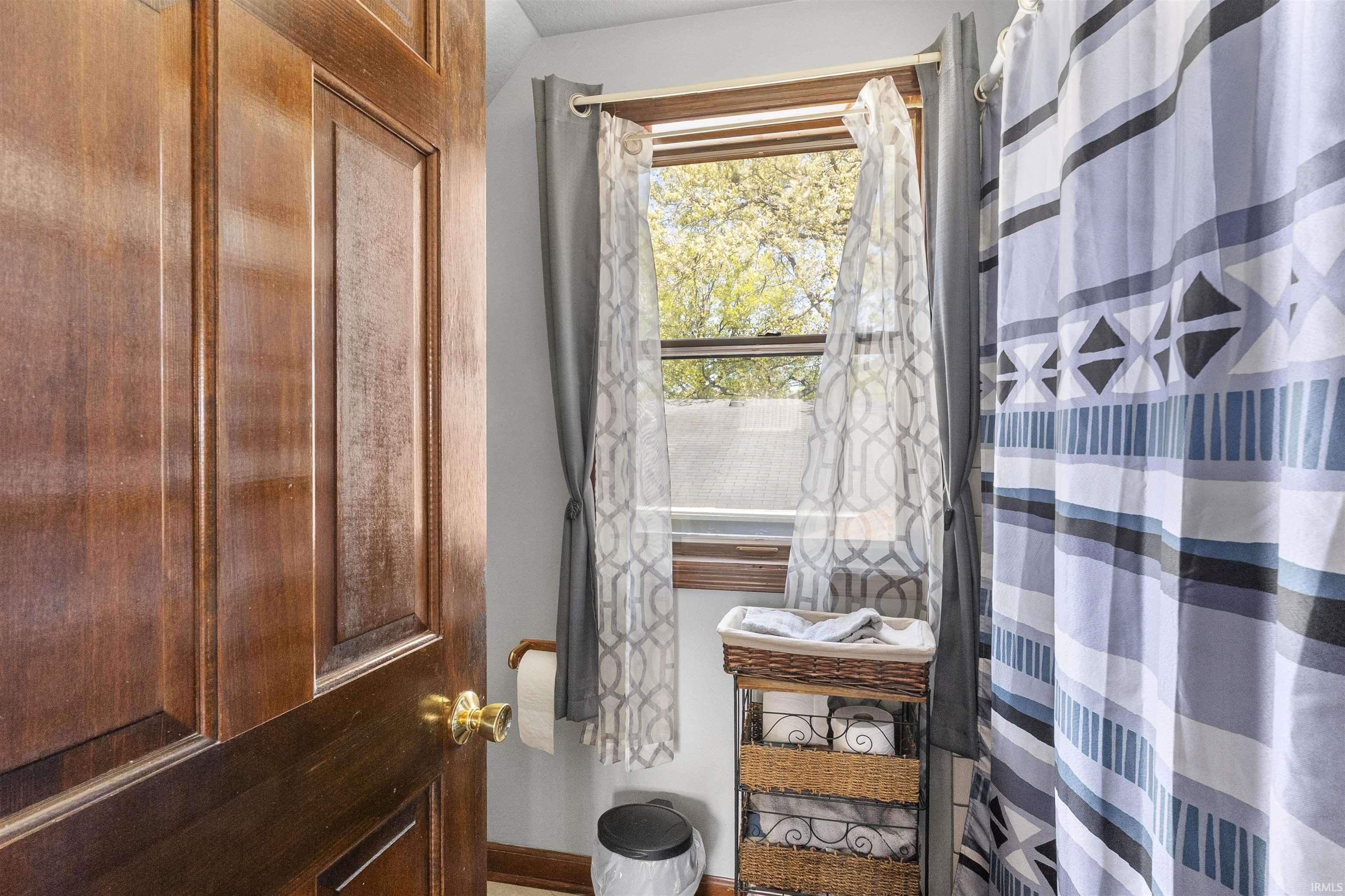 Wood-paneled door with brass hardware and a window featuring a wood frame