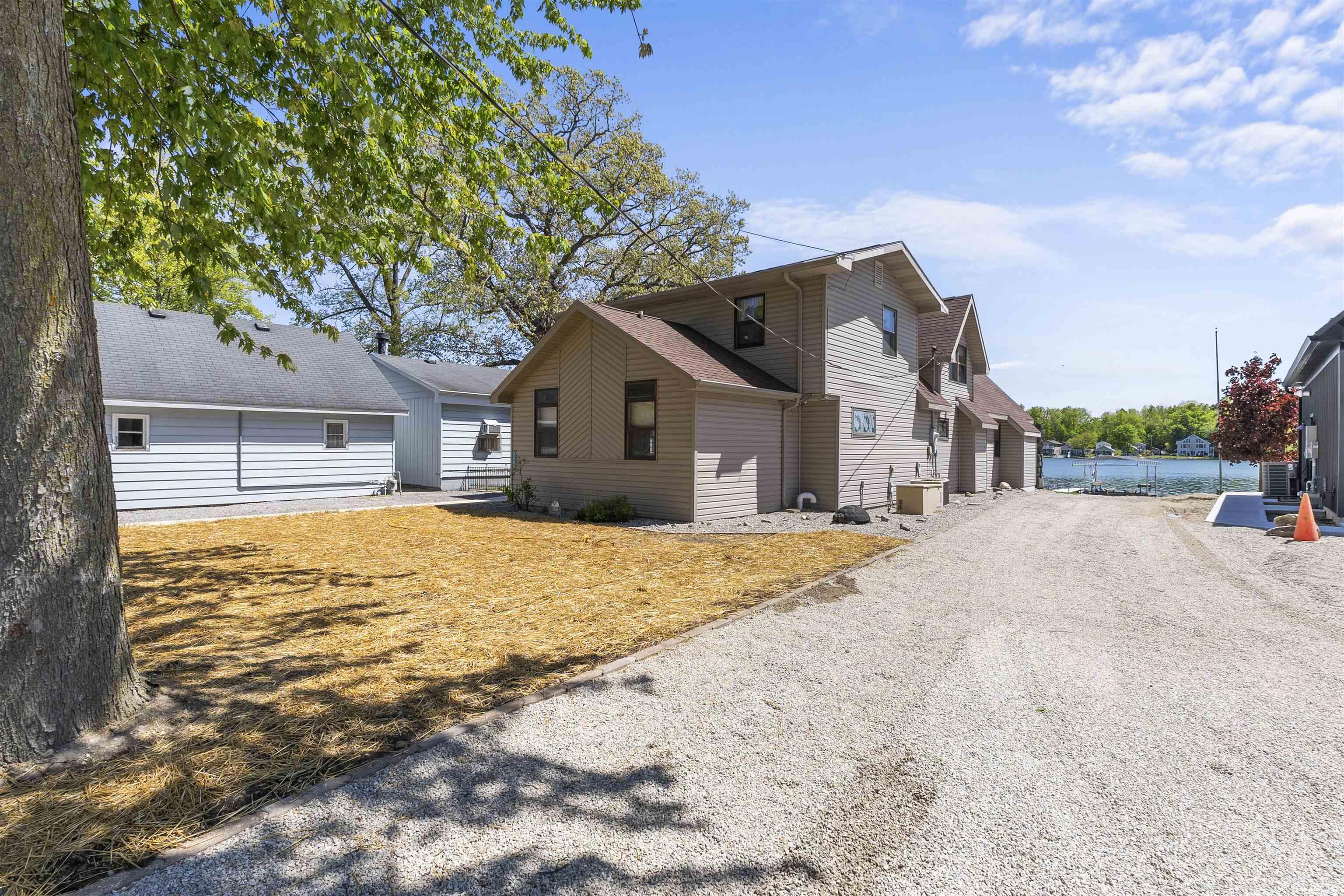 Gravel driveway leading to multiple structures with water frontage
