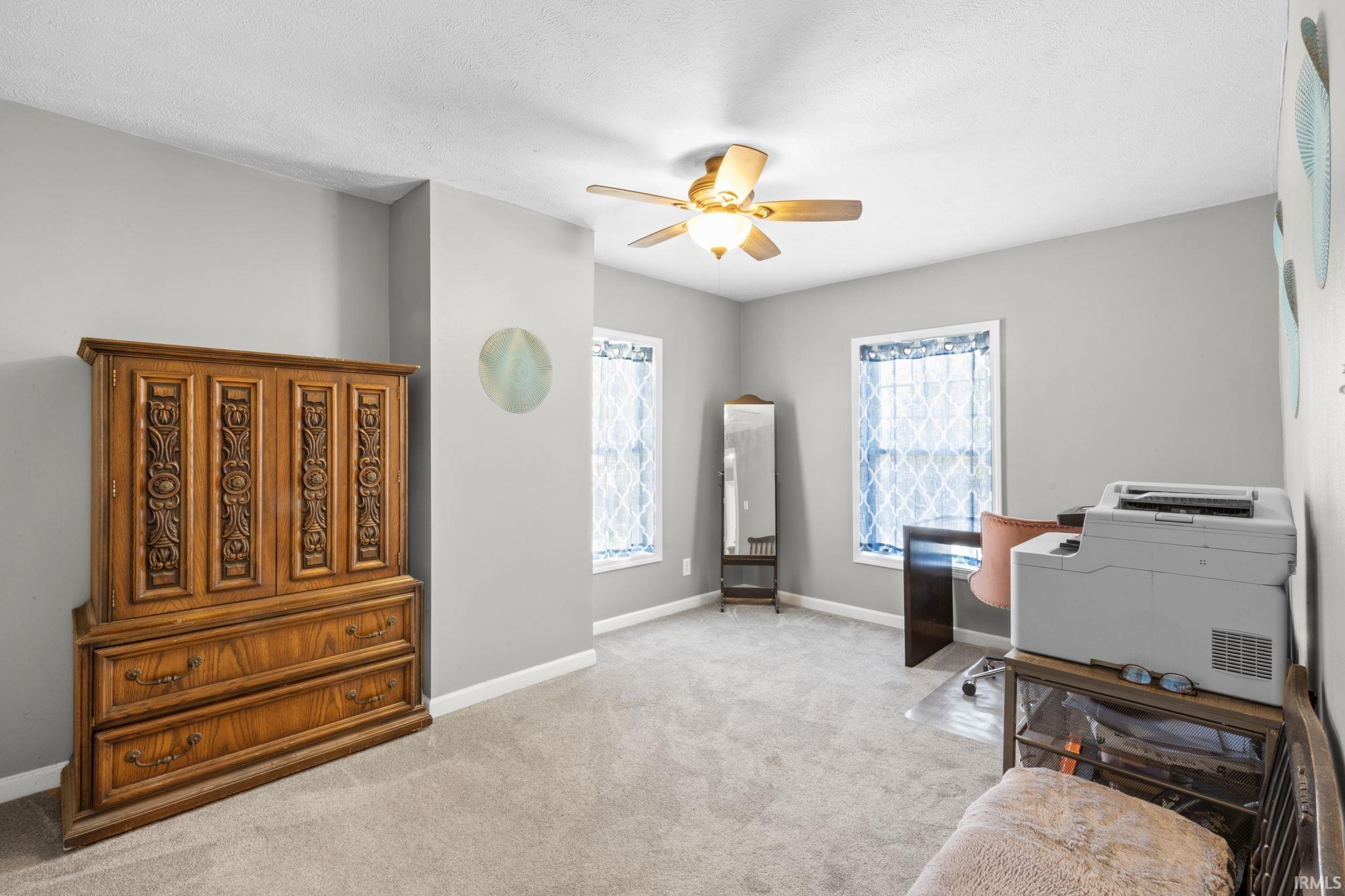 Carpeted room with light gray walls, two windows, and a ceiling fan