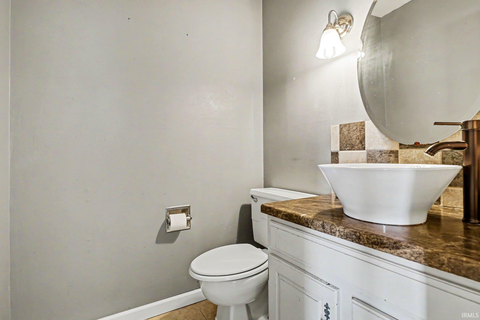 White vessel sink with a bronze-toned faucet, set on a dark patterned countertop