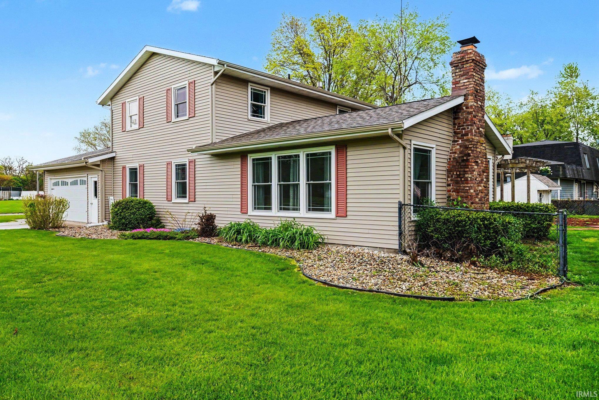 Two-story home featuring light-toned horizontal siding with red window shutters