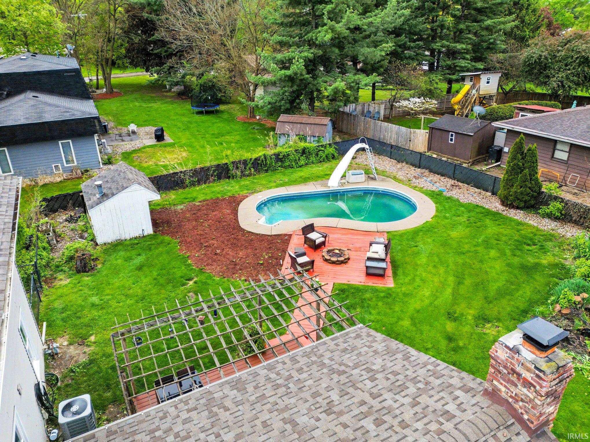 Expansive backyard featuring an in-ground swimming pool, surrounding patio, and dedicated fire pit area