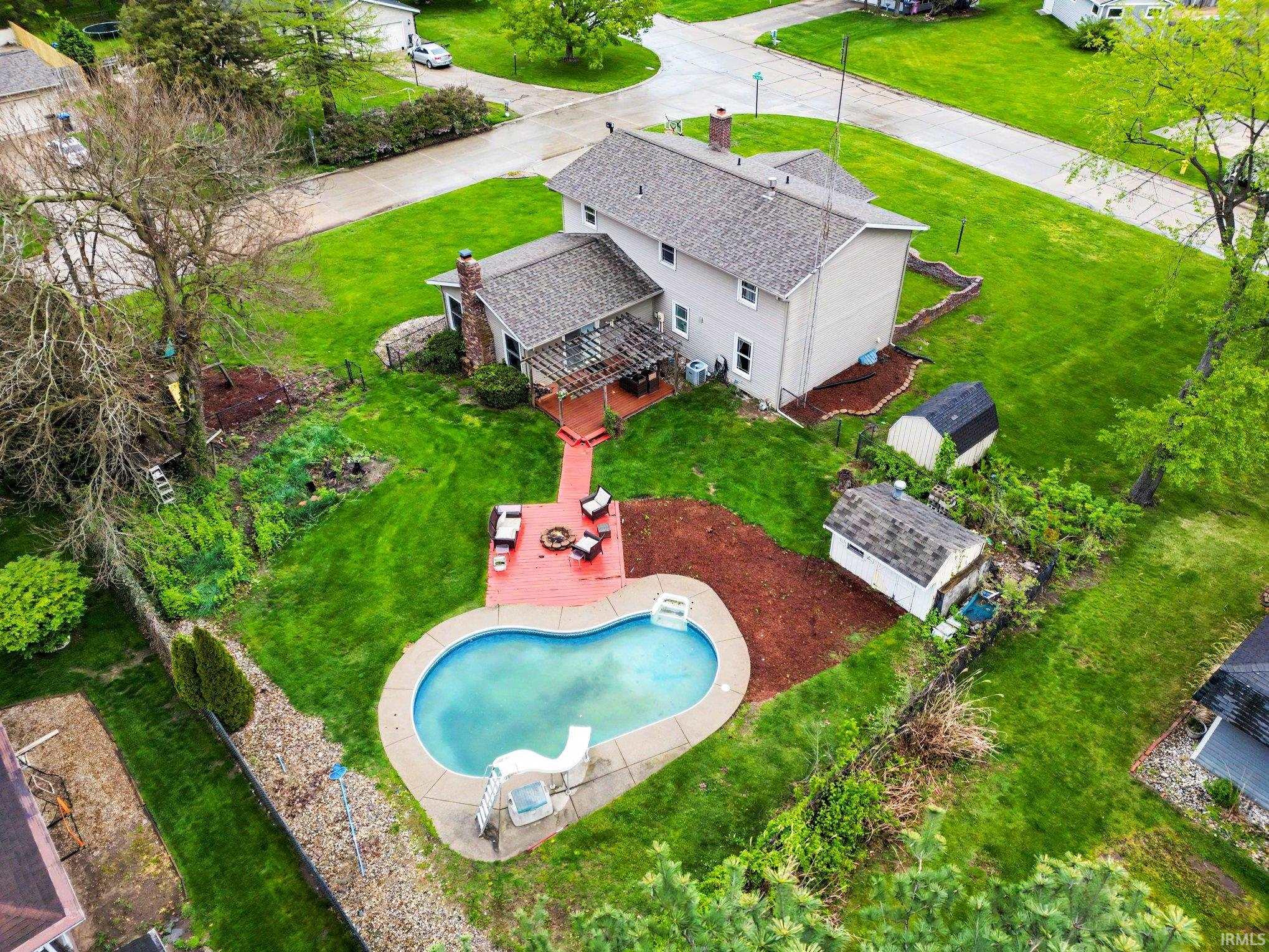 Expansive backyard featuring a kidney-shaped in-ground pool with a slide, a red-stained deck, and a pergola