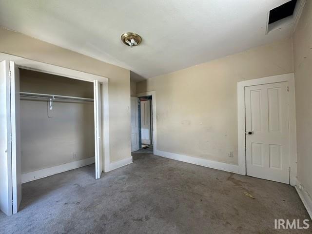 Room featuring a flush-mount ceiling light fixture, a paneled interior door with dark hardware, and a closet with bifold doors and built-in hanging rods