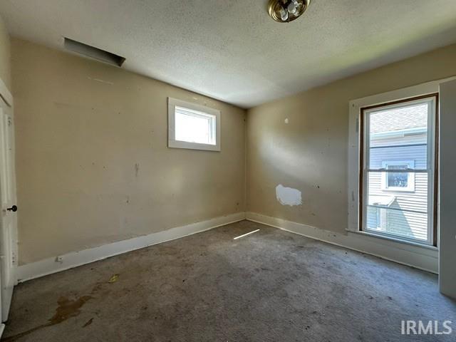 Interior room featuring two windows, an overhead light fixture, a ceiling vent, and baseboard trim