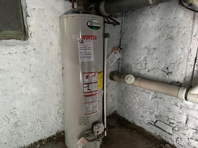 Water heater with visible piping and painted brick walls