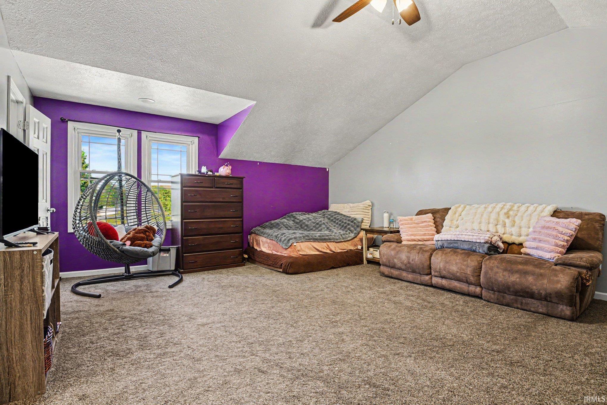 Carpeted room with sloped ceilings, two windows, and a ceiling fan