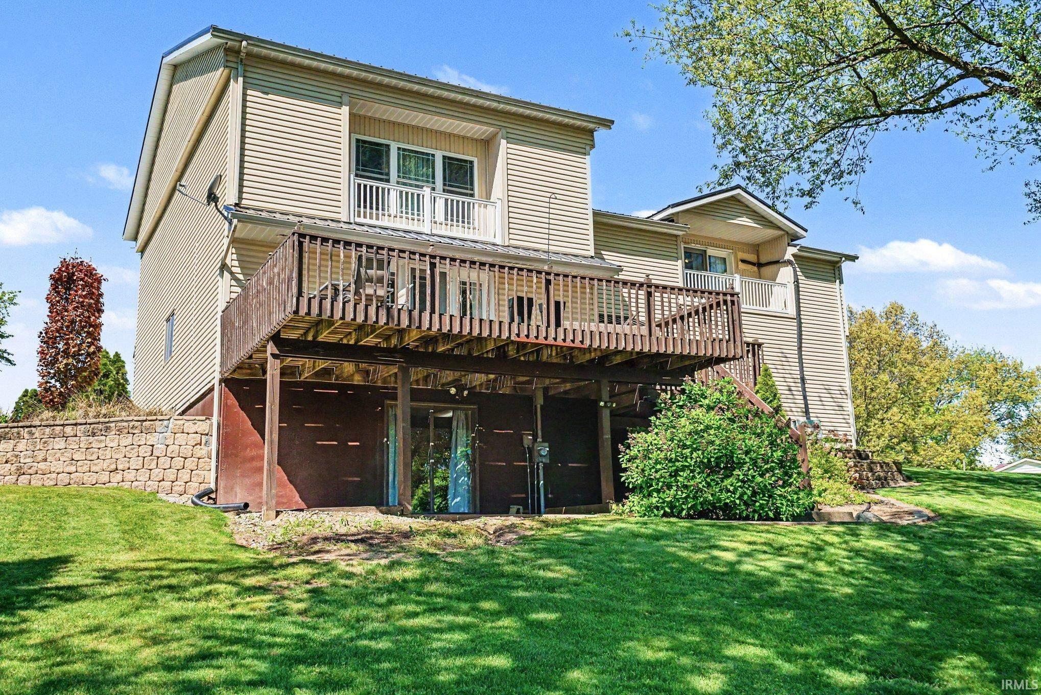 Expansive rear exterior featuring a multi-level deck, lower patio access, and a second-story balcony
