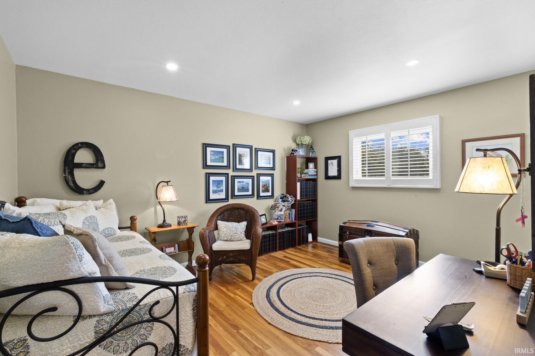 Room featuring wood-finish flooring, recessed lighting, and a window with plantation shutters