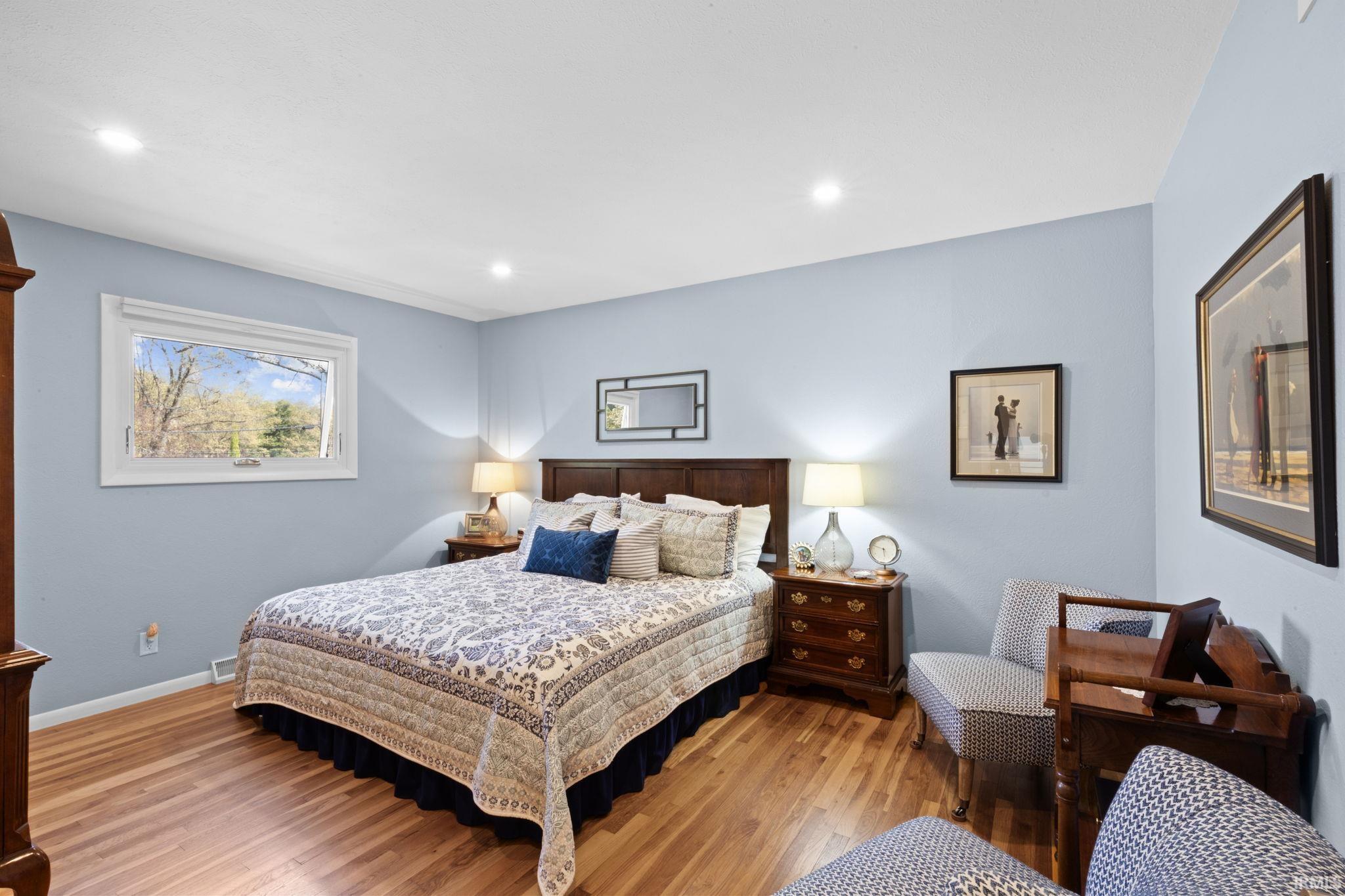 Bedroom featuring wood-finish flooring, recessed lighting, and a broad window