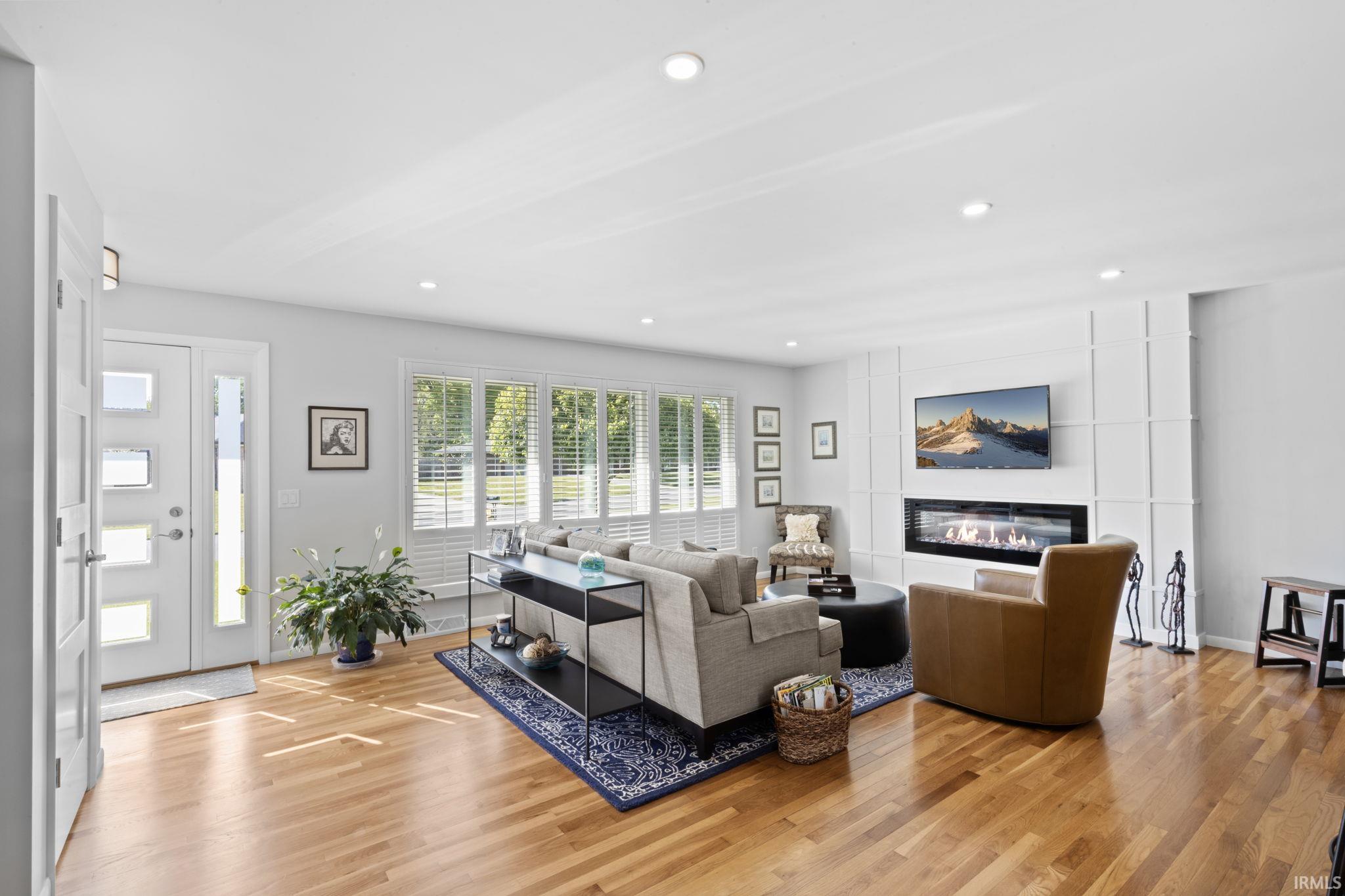 Spacious living area featuring wood-finish flooring, a contemporary linear fireplace, and recessed lighting