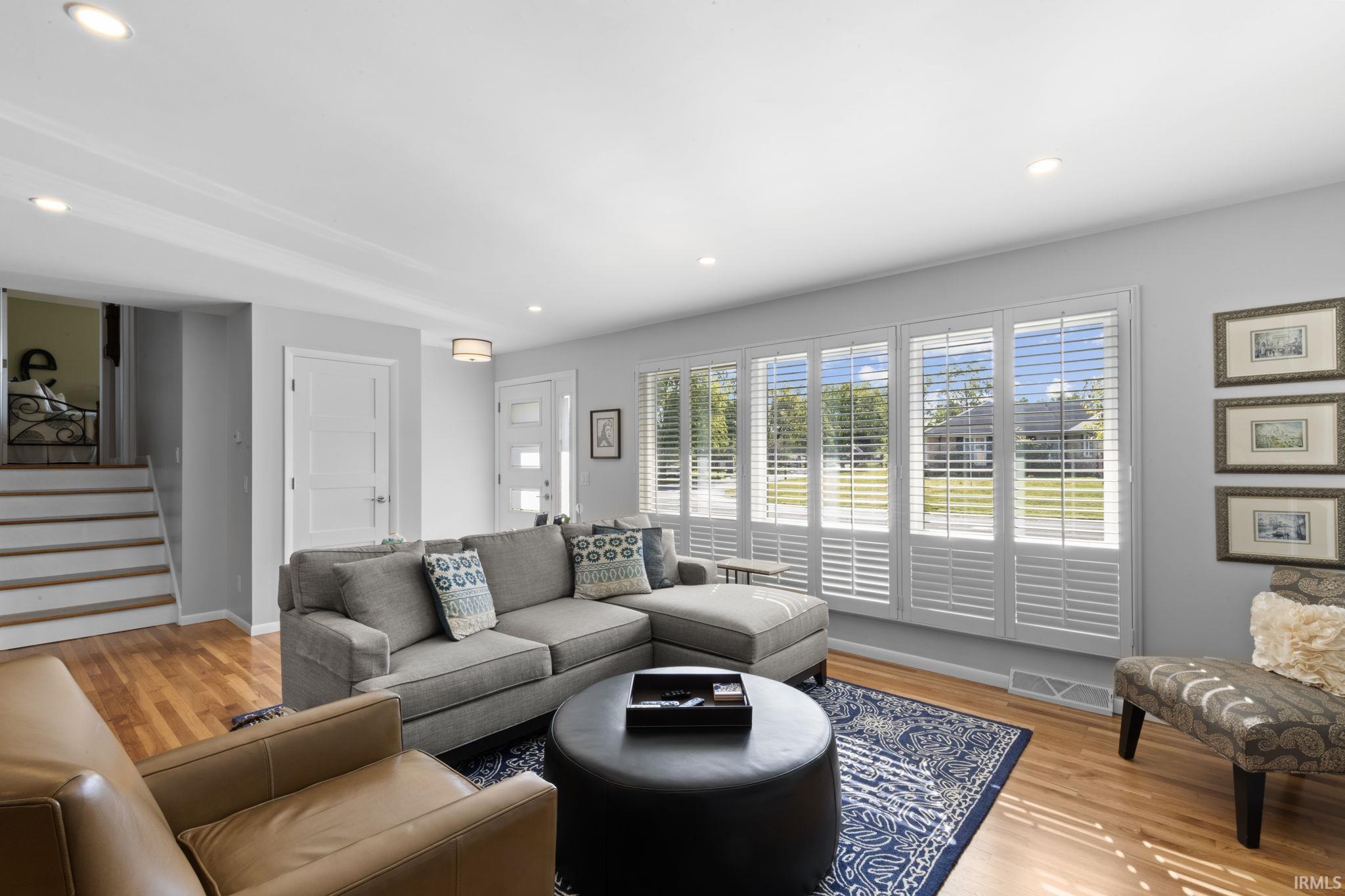 Living area featuring hardwood flooring, recessed lighting, and a multi-panel window with white plantation shutters
