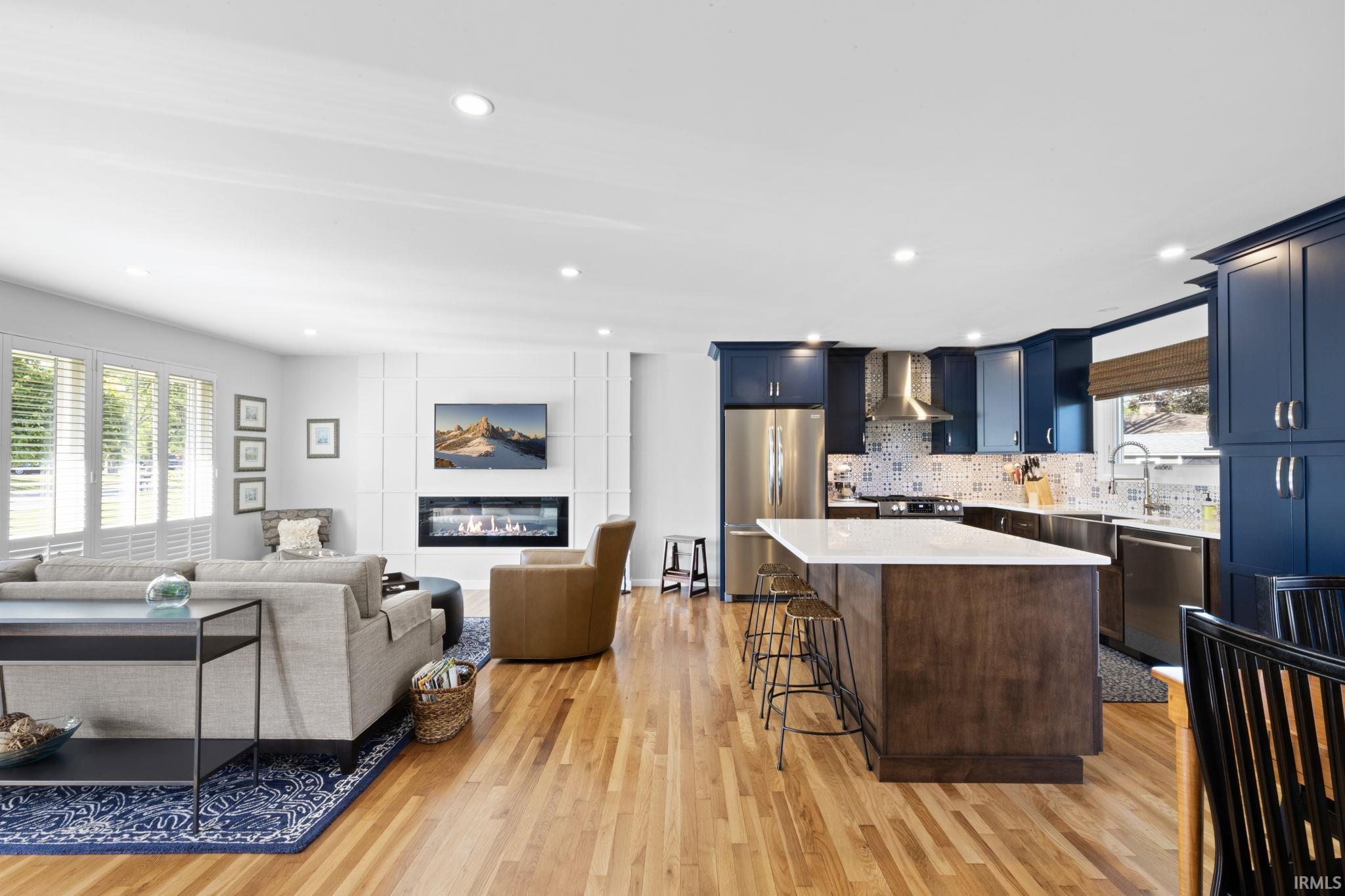 Open-concept living space featuring wood-finish flooring, recessed lighting, and a linear electric fireplace