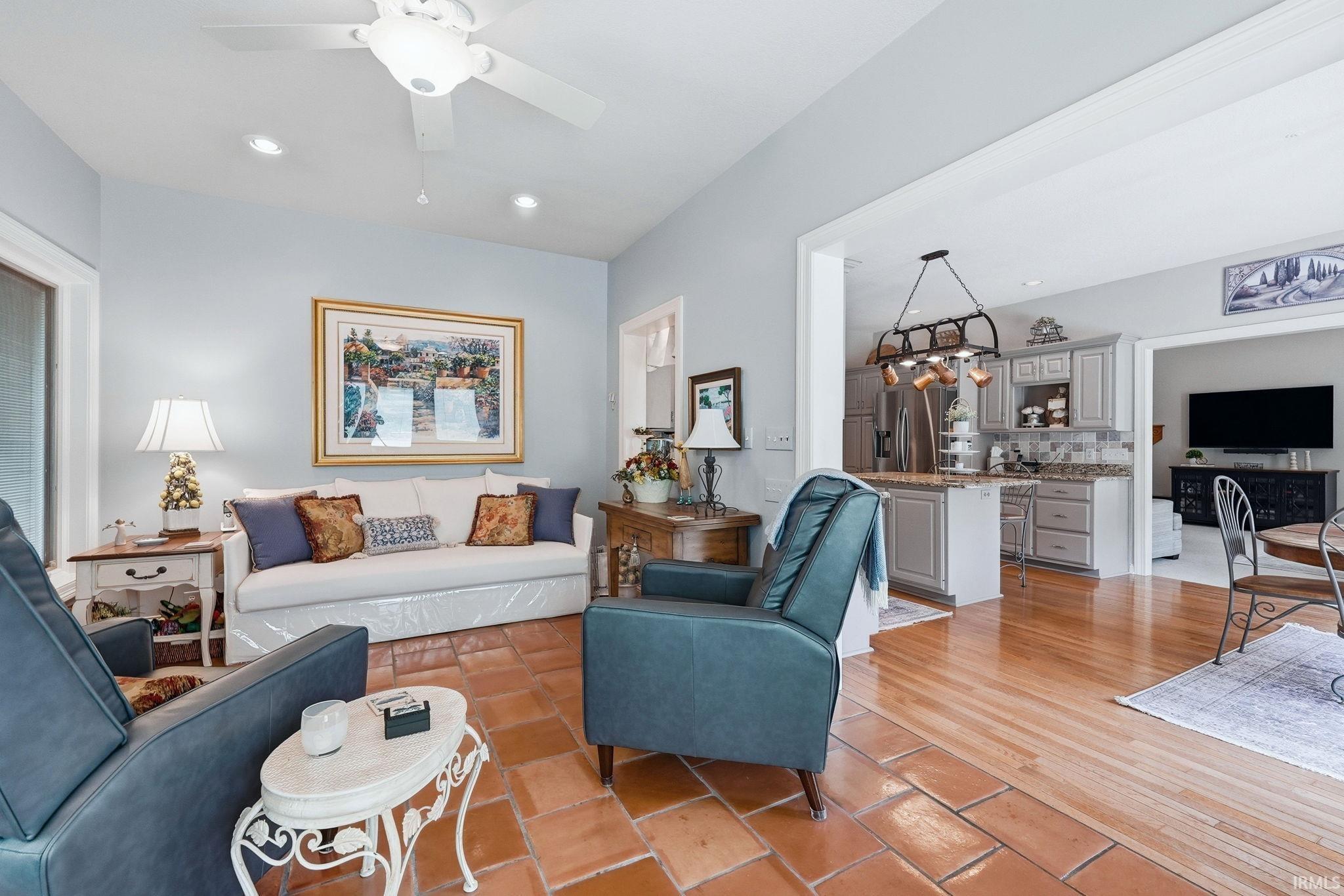 Living area with terracotta tile flooring and a vaulted ceiling with a fan