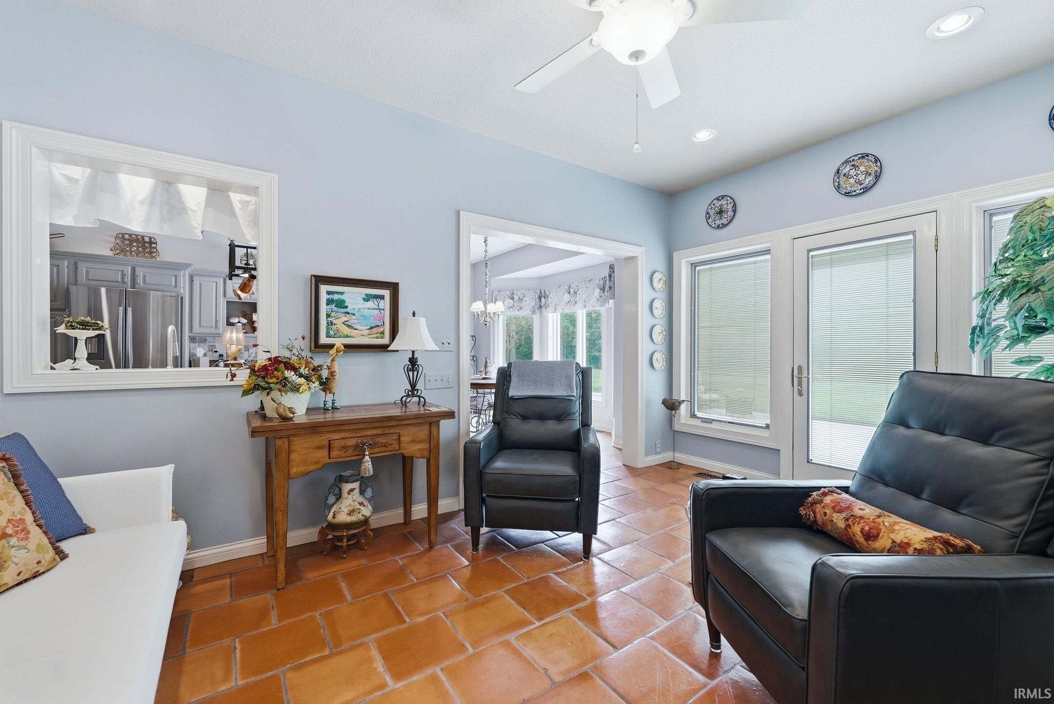 Informal living space featuring terracotta tile flooring, light blue wall finishes, and a ceiling fan with integrated lighting