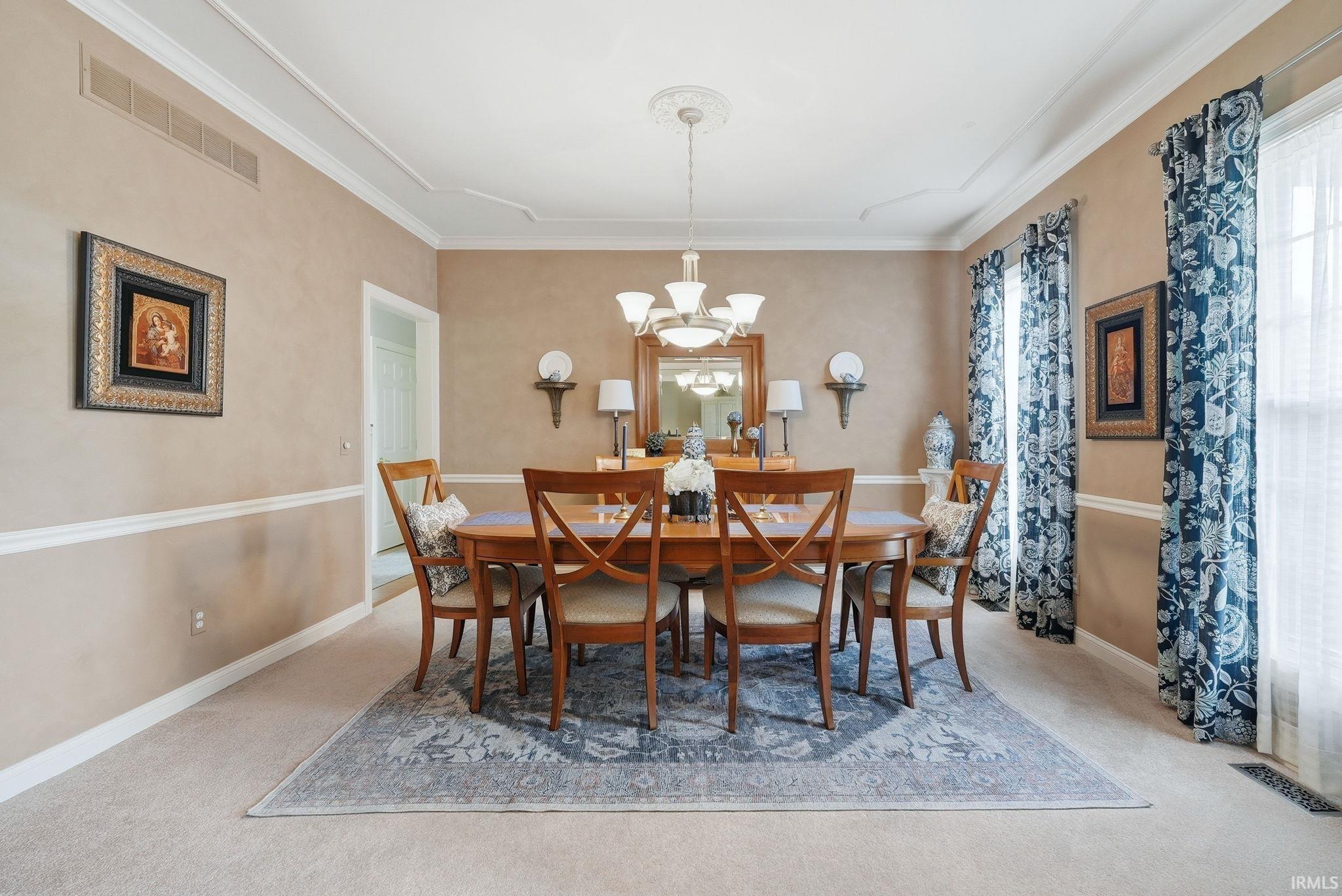 Formal dining room featuring crown molding, chair rail molding, a decorative ceiling medallion, an elegant chandelier, and expansive windows