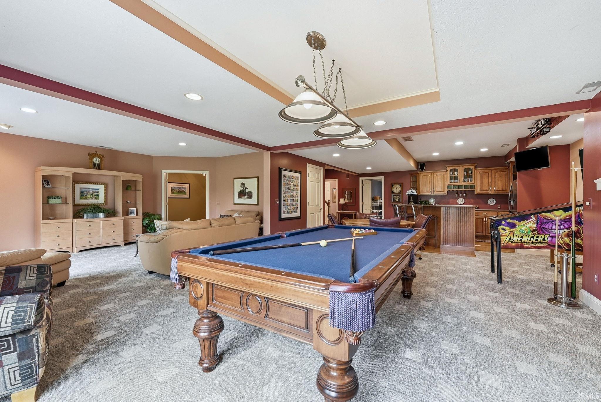 Spacious recreation room featuring recessed lighting, a built-in wet bar with wooden cabinetry, and a dropped ceiling with decorative trim