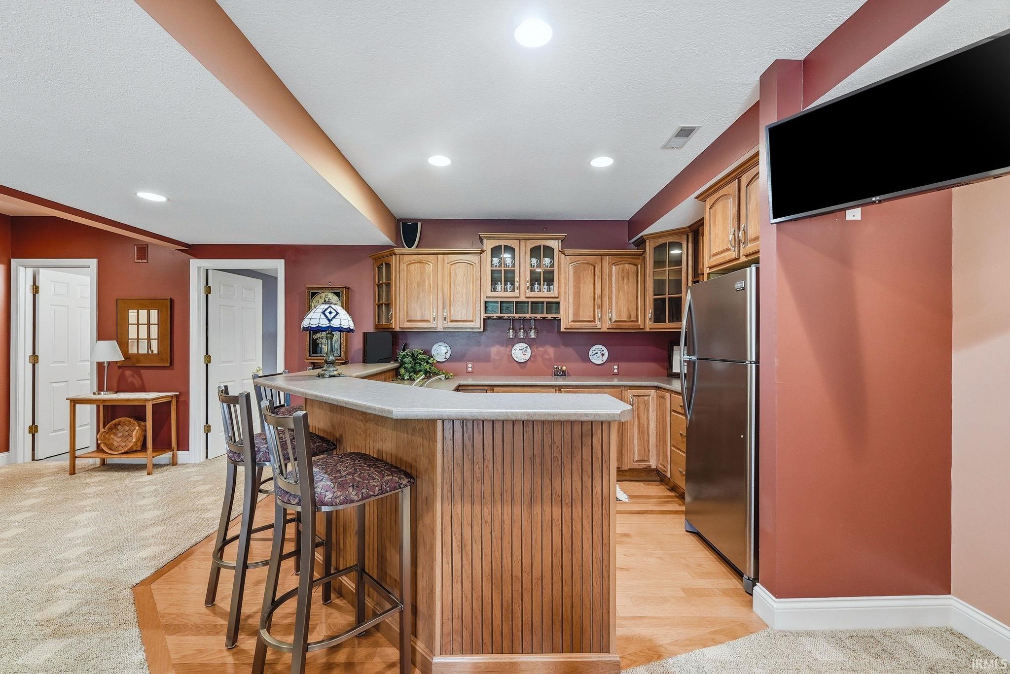 Entertainment space featuring a wood-finish bar with a light-toned countertop, recessed lighting, and wood-finish cabinetry