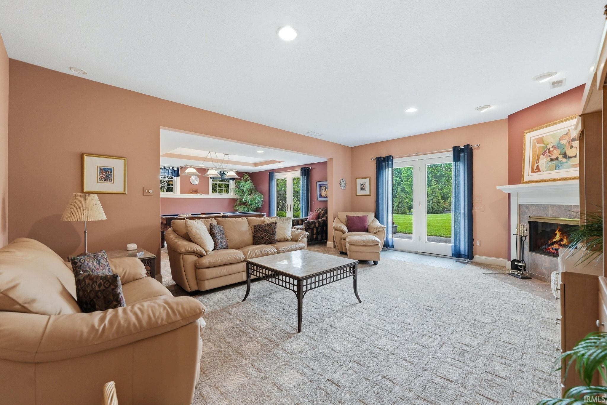 Expansive living area with patterned carpeting and a wood-burning fireplace featuring a white mantel