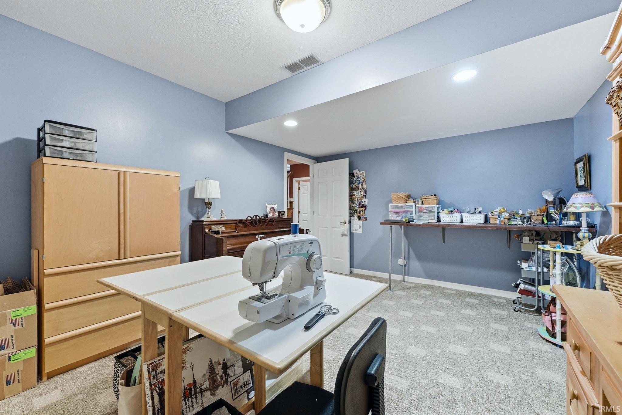 Versatile room featuring light blue walls, recessed lighting, and patterned carpet flooring