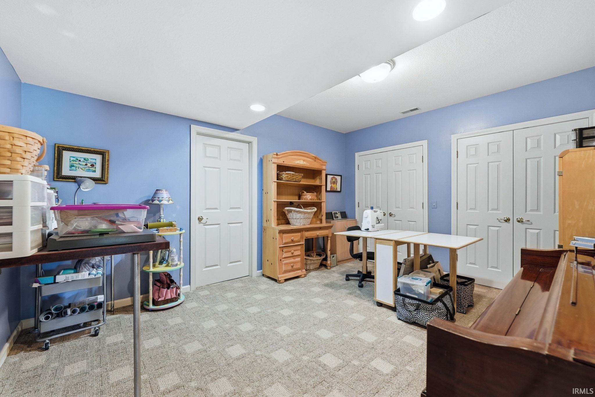 Finished room featuring light blue walls, recessed lighting, and patterned carpet flooring