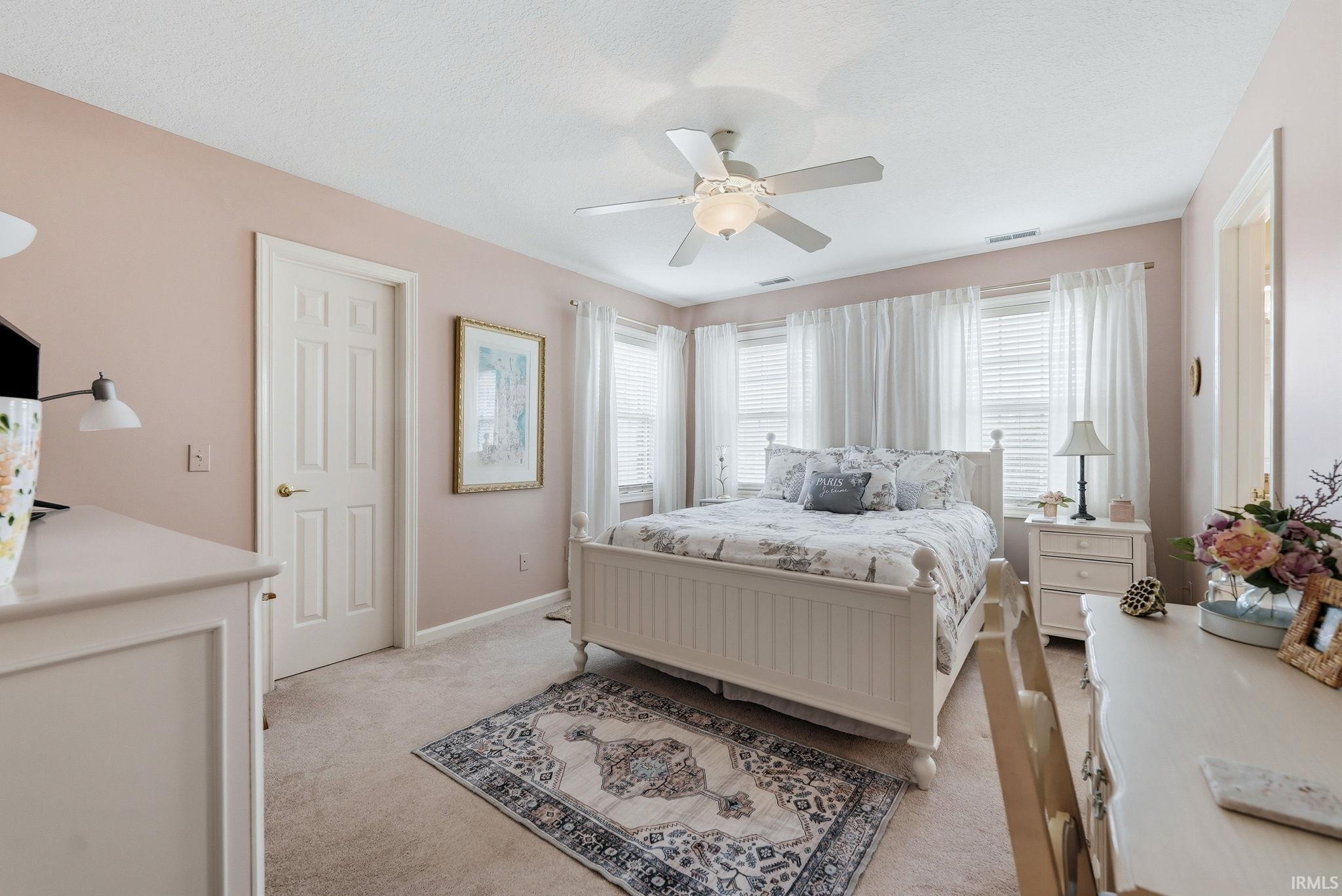 Carpeted bedroom featuring soft wall tones and a multi-light ceiling fan