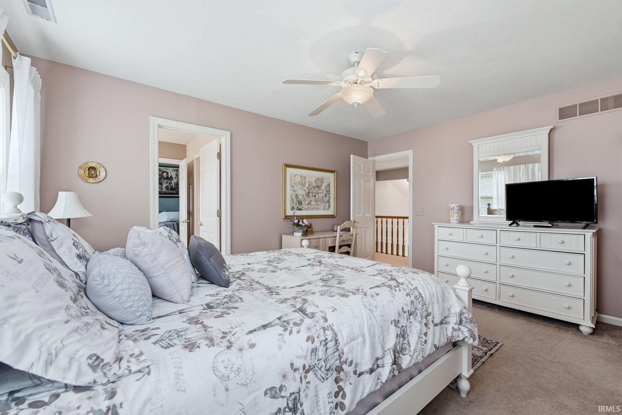 Spacious bedroom featuring neutral wall tones, carpeted flooring, and a ceiling fan