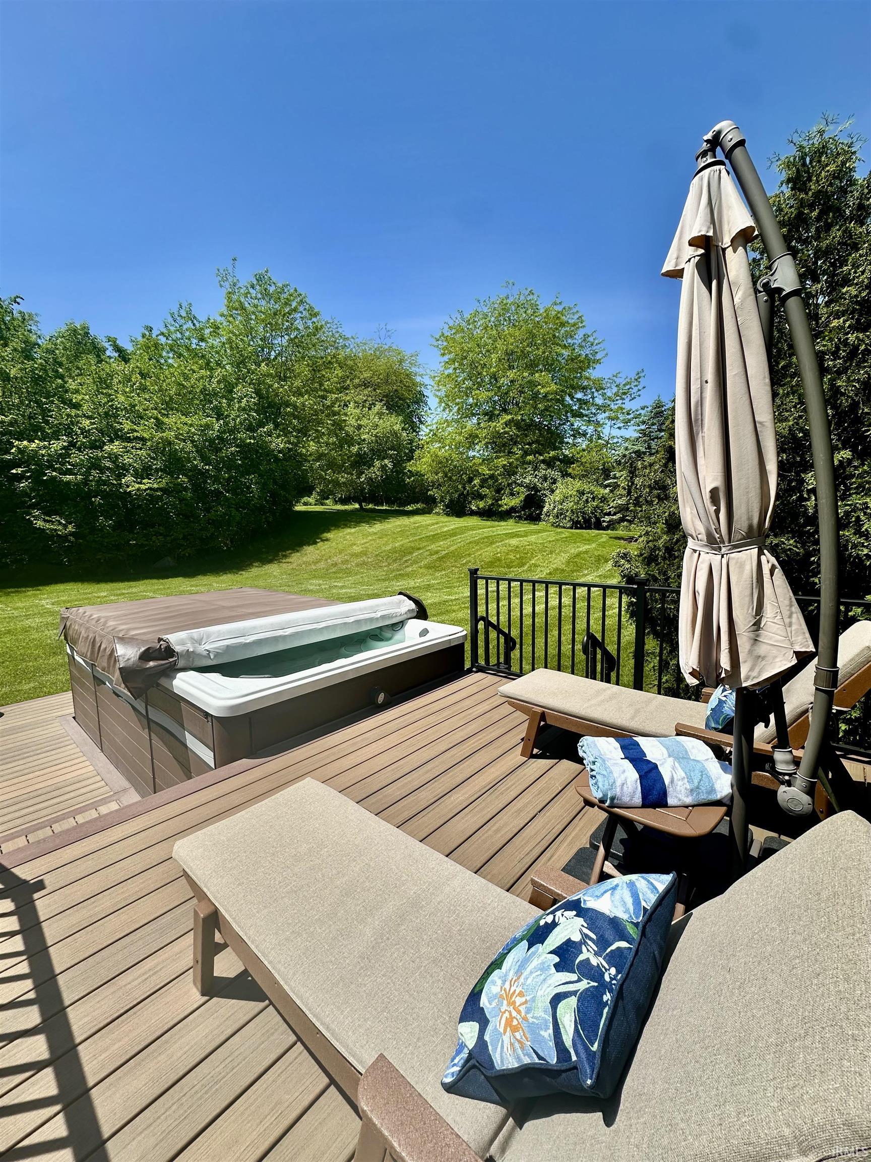 Spacious outdoor deck featuring swim spa, trex decking, and black metal railings.