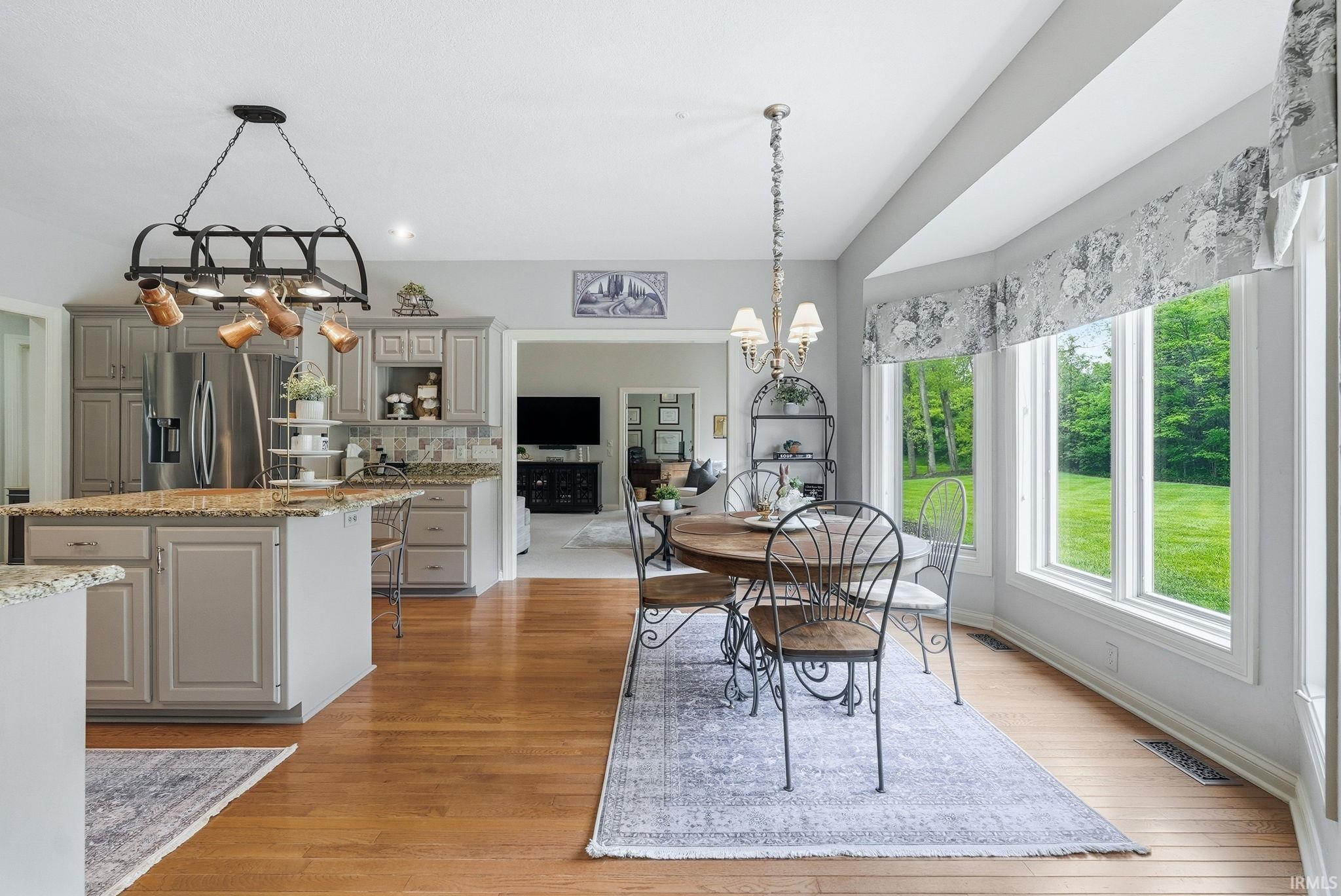 Kitchen and dining area featuring wood-finish flooring, recessed lighting, and a bay window overlooking a green landscape