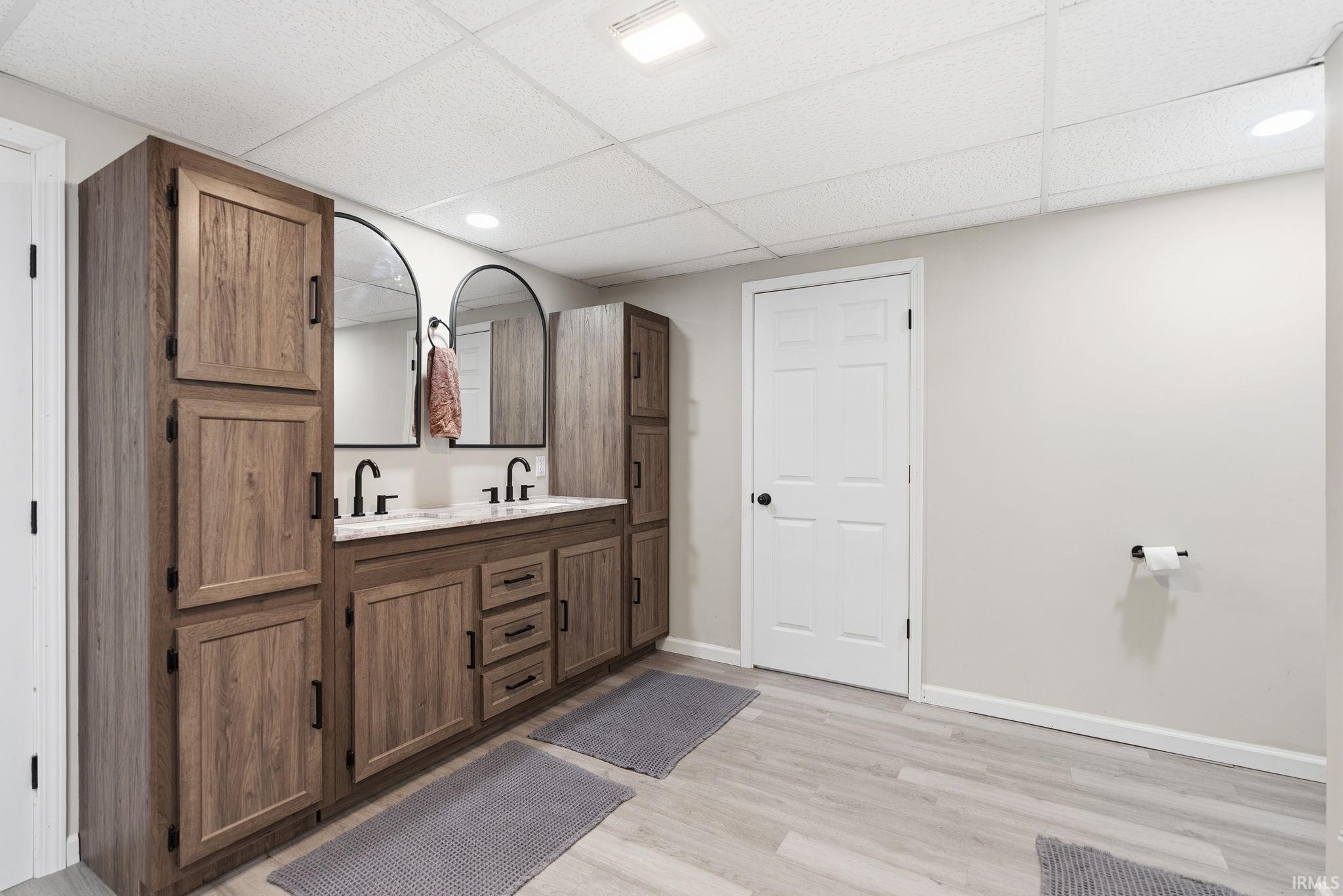 Dual vanity with wood-finish cabinetry, black hardware, and two arched mirrors